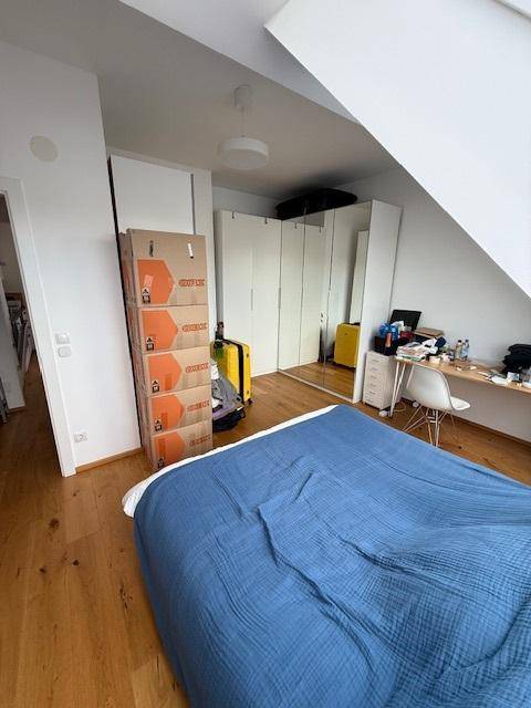 Schlafzimmer im Dachgeschoss mit Holzboden, integrierten Kleiderschränken und schräger Decke.