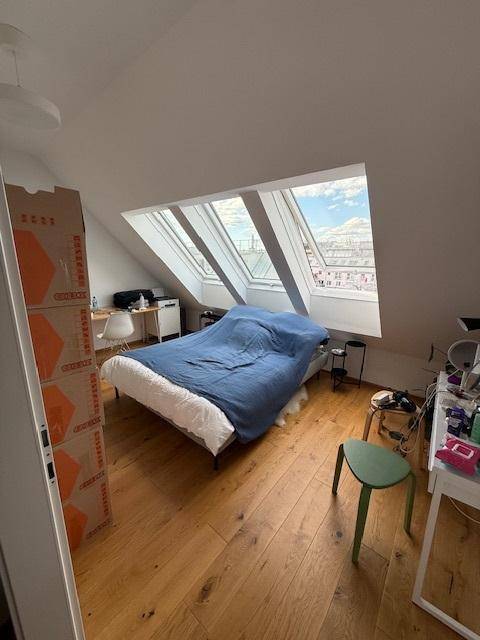 Helles Schlafzimmer im Dachgeschoss mit Holzboden, schrägen Wänden und großen Dachfenstern.