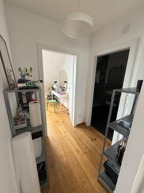 Heller Flur mit Holzboden, der zu weiteren Räumen führt und eine offene Gestaltung aufweist.