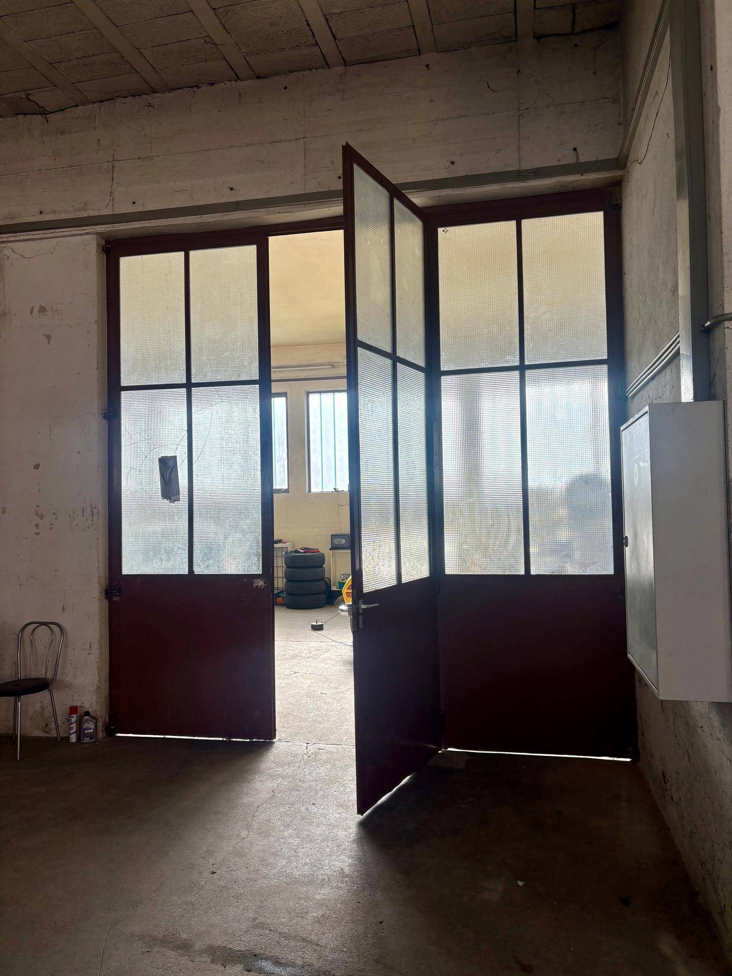 Große Doppeltüren mit Glaspaneelen führen in einen weiteren Bereich der Lagerhalle.