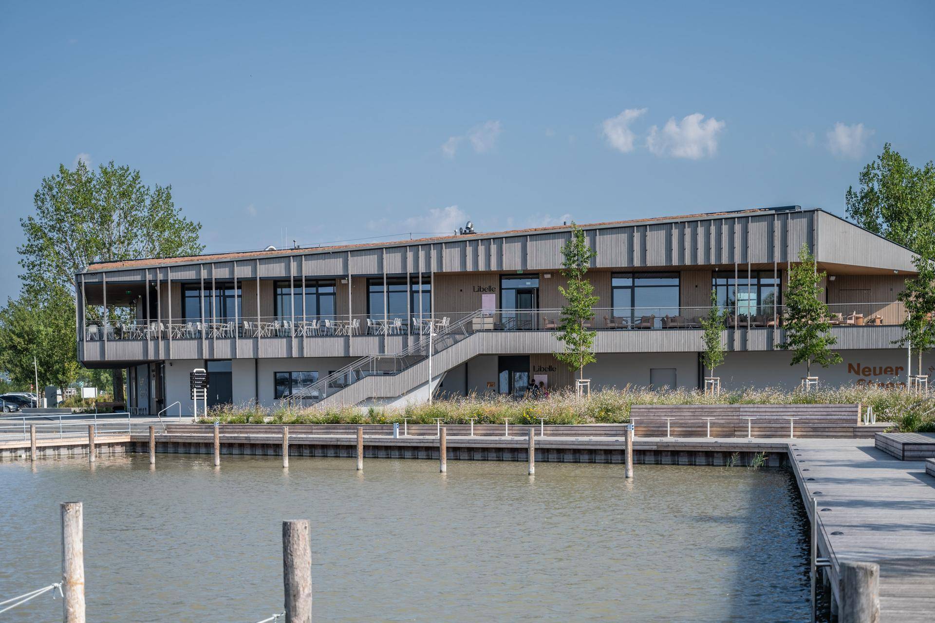 Modernes Gebäude mit Terrassen und großen Fenstern direkt am Wasser, umgeben von Holzstegen.