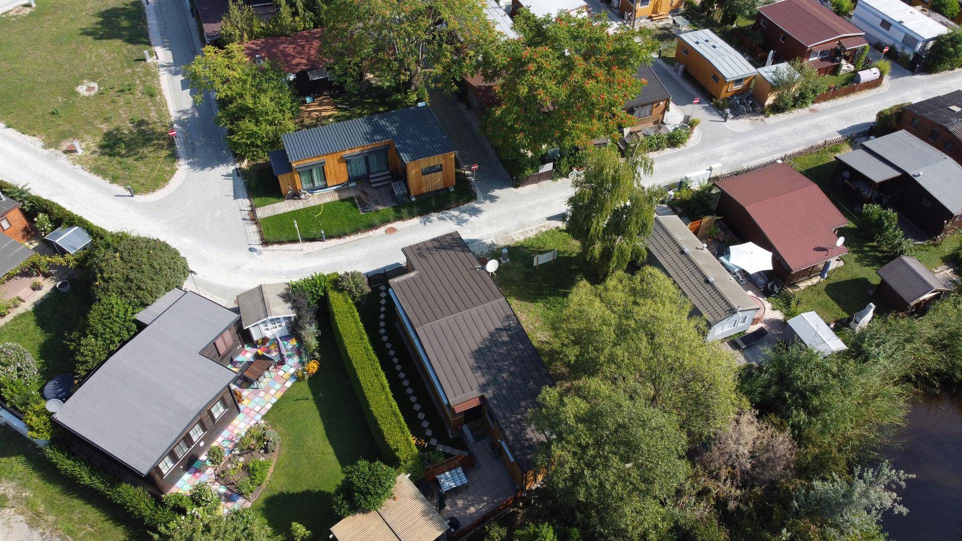 Luftaufnahme einer Wohnsiedlung mit mehreren Häusern, Straßen und viel Grünfläche.