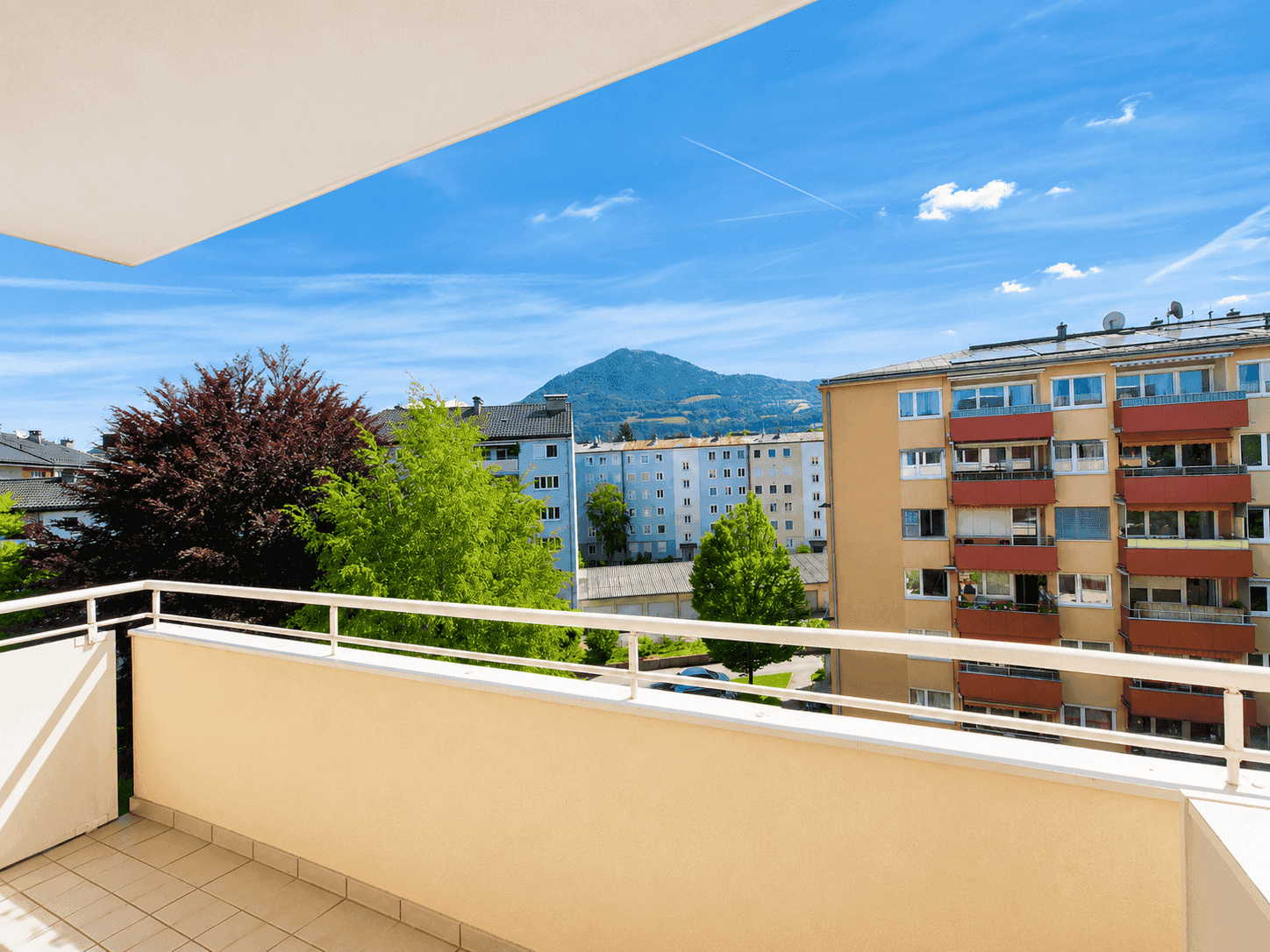 Geräumiger Balkon mit Bergblick und Aussicht auf die umliegenden Gebäude.