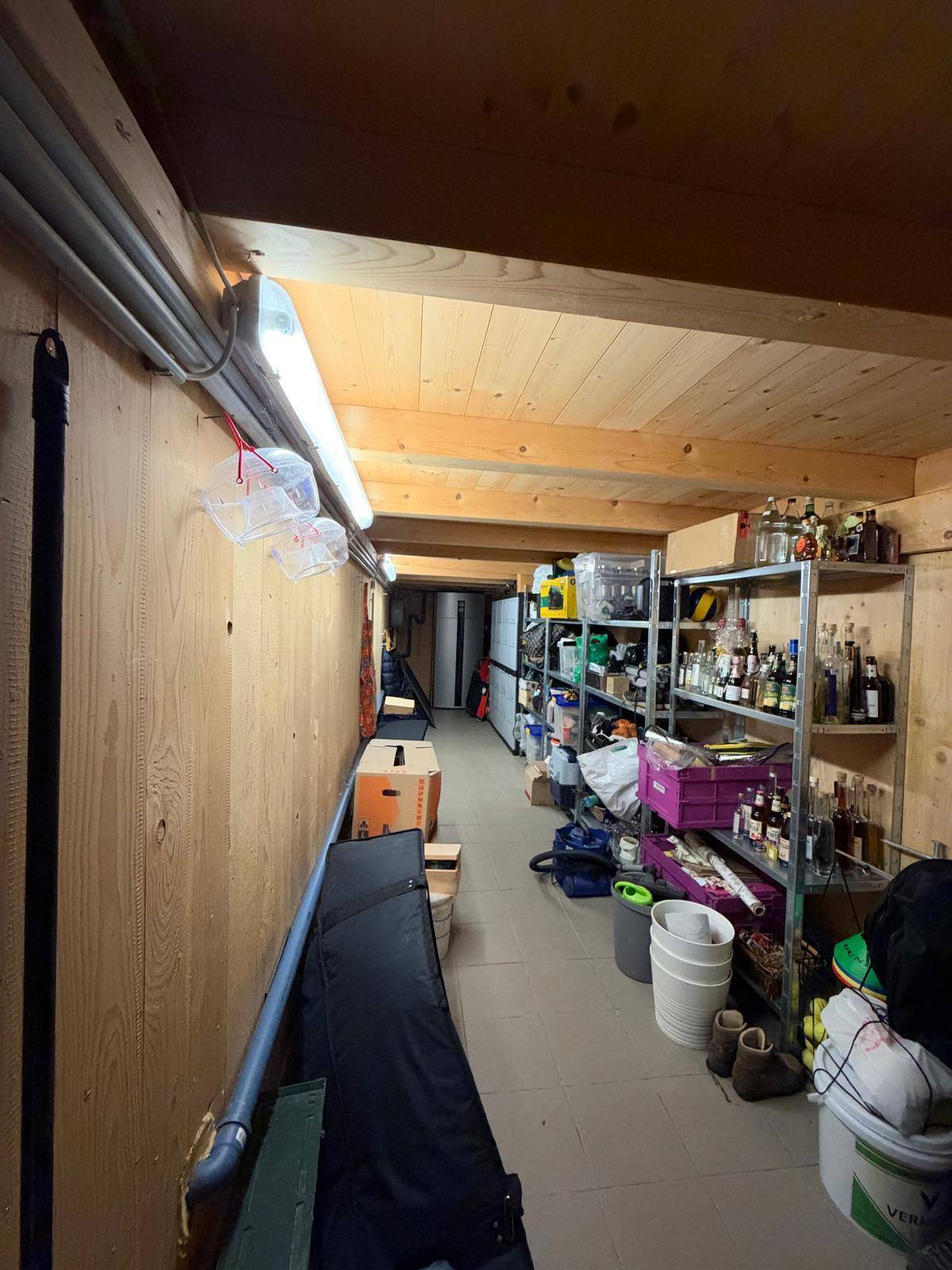 Geräumiger Abstellraum mit Holzverkleidung, Regalen und verschiedenen Lagergegenständen.