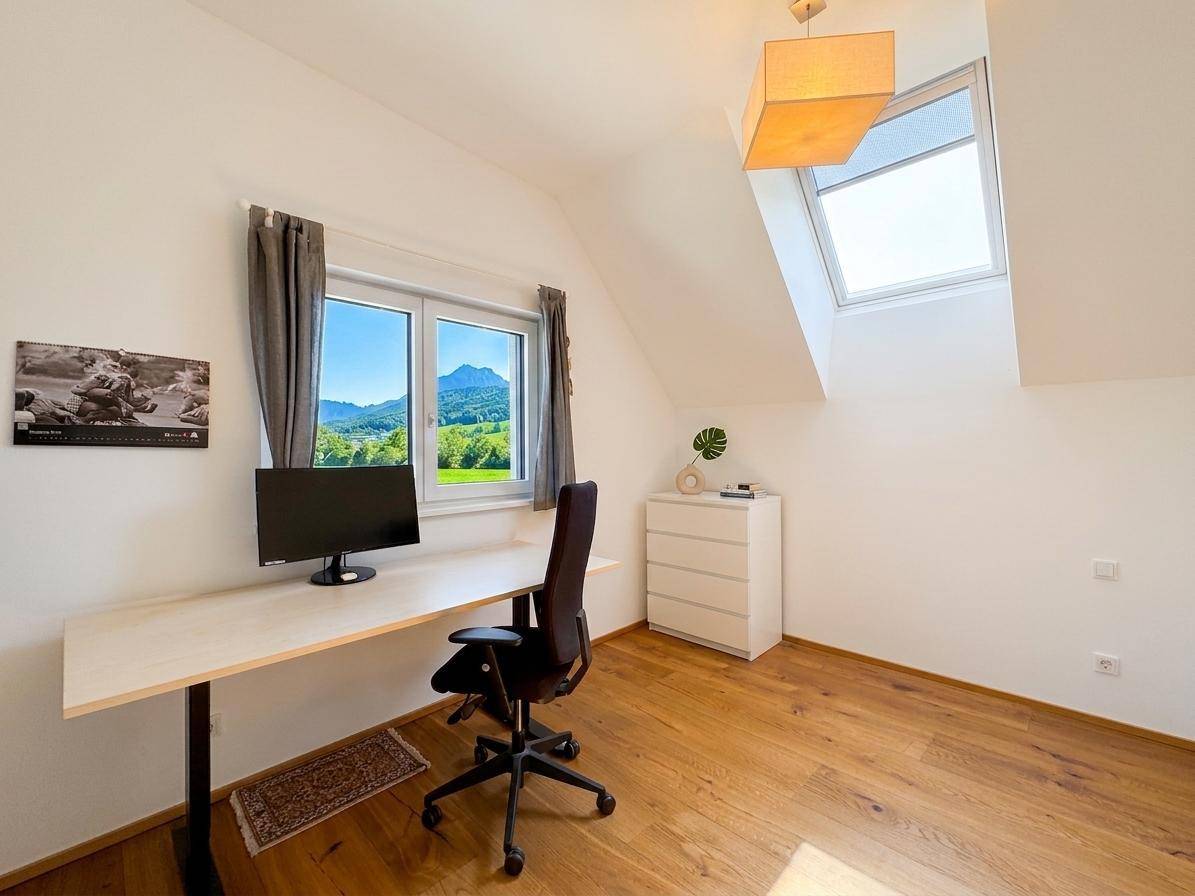 Arbeitszimmer im Dachgeschoss mit Schreibtisch, Bergblick und viel Tageslicht durch Fenster.