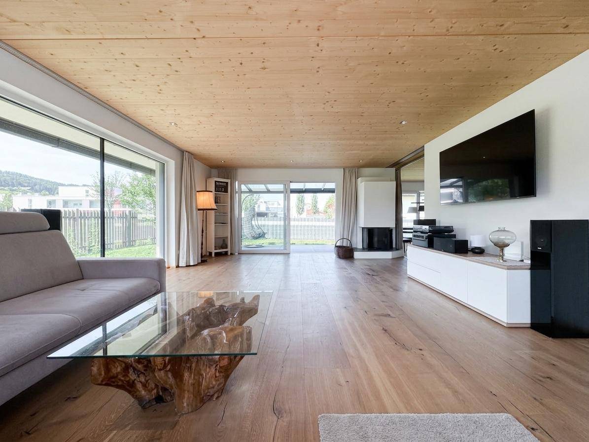 Helles Wohnzimmer mit Holzboden, großen Fenstern und einem modernen Kamin.