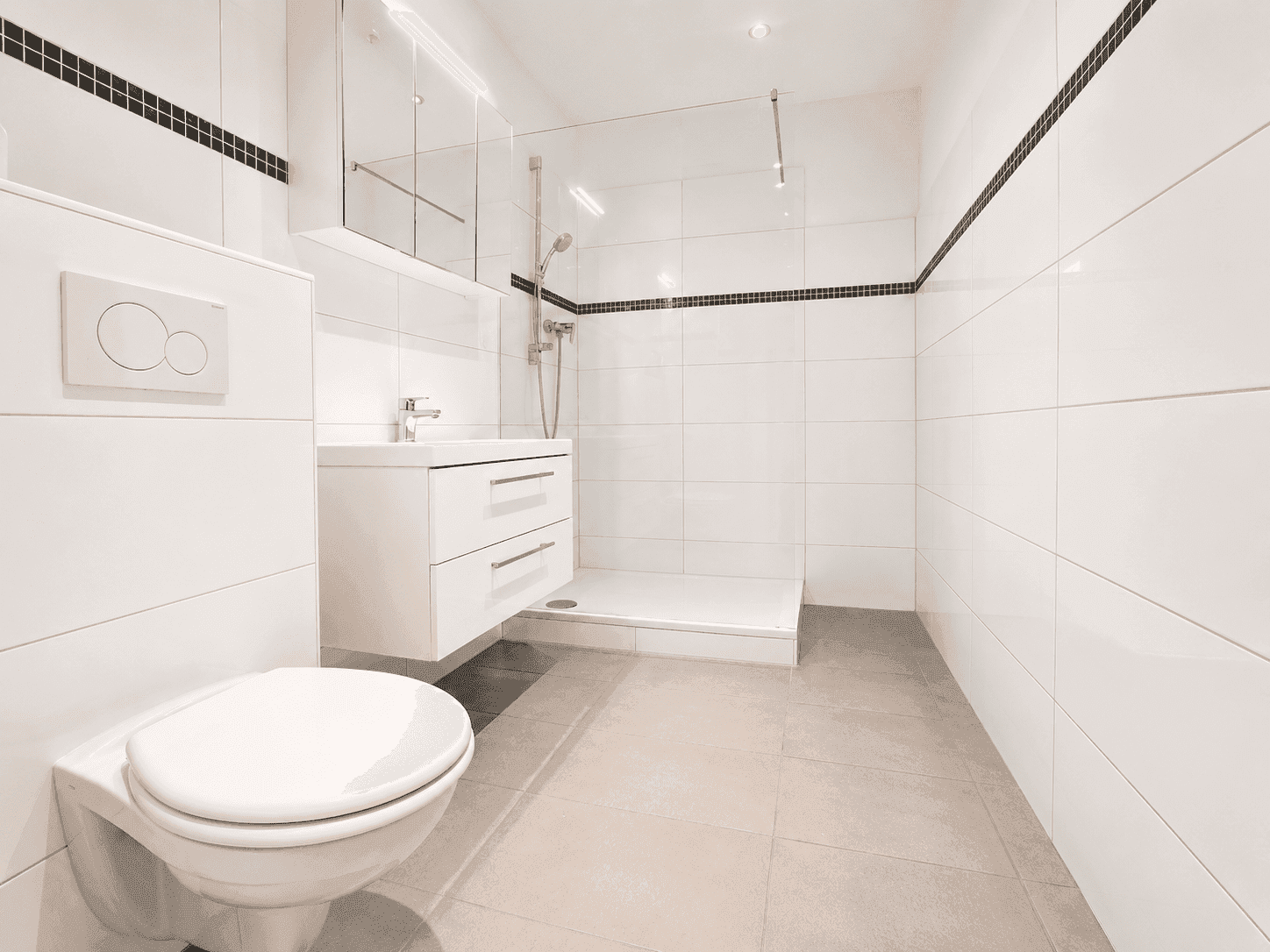 Modernes Badezimmer mit weißen Fliesen, Dusche und wandhängendem WC, sehr gepflegt.