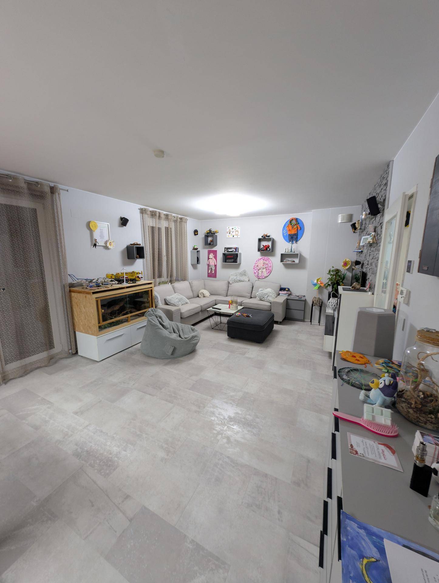 Gemütliches Wohnzimmer mit großem Ecksofa, modernem Bodenbelag und individueller Dekoration.