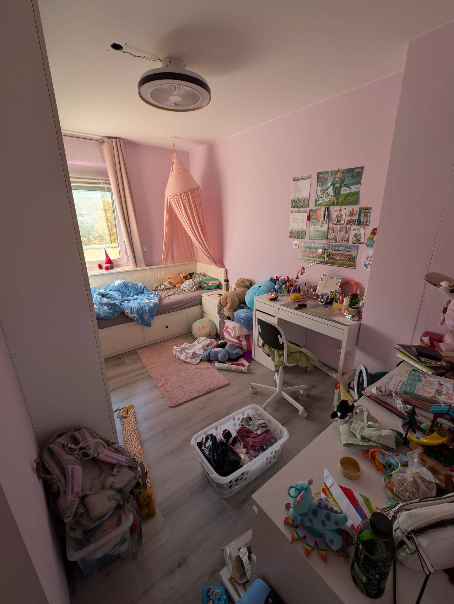 Kinderzimmer mit rosa Wänden, Bett, Schreibtisch und Spielzeug, hell und freundlich gestaltet.