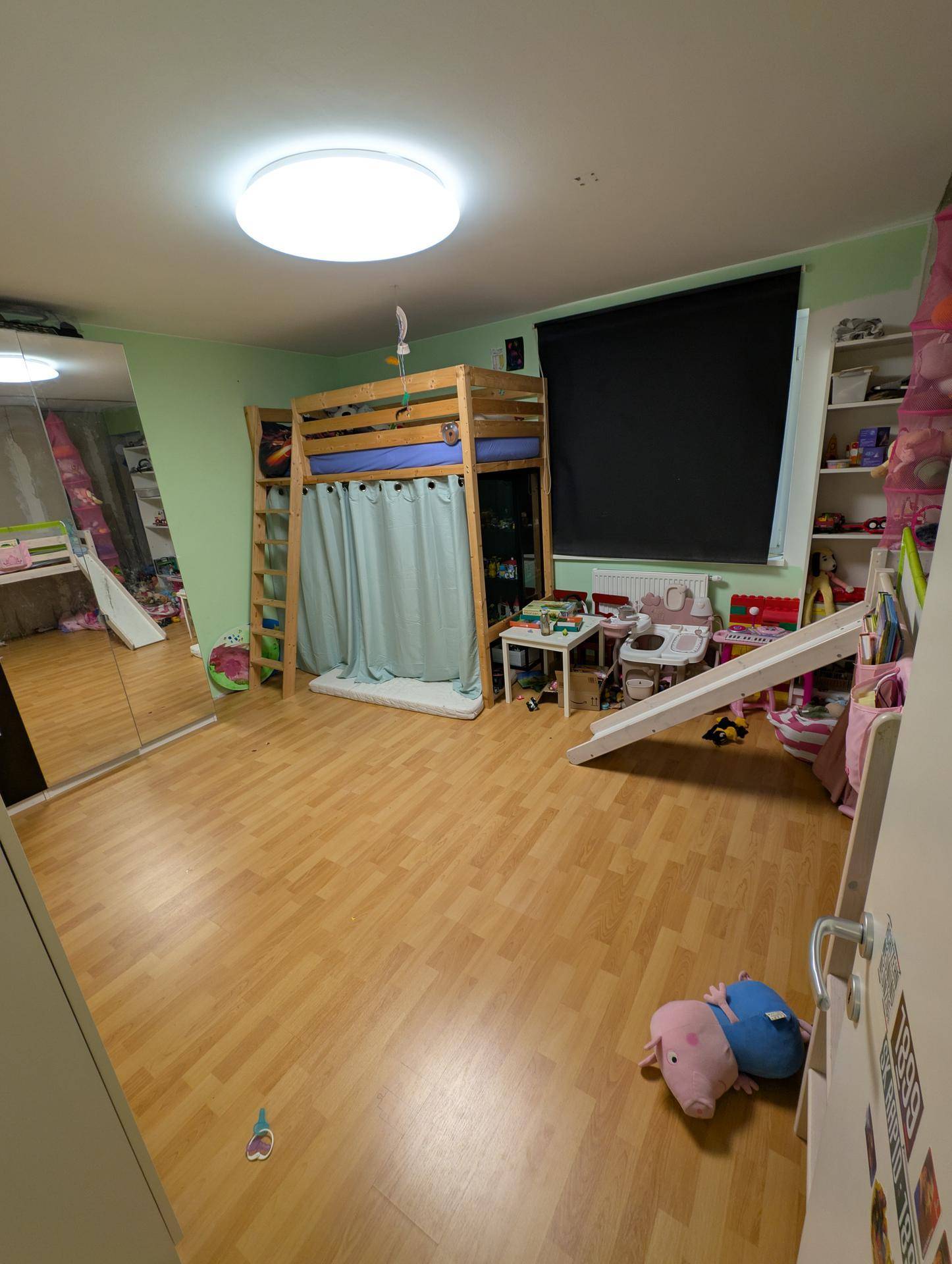 Geräumiges Kinderzimmer mit Hochbett, Rutsche und Holzfußboden, ideal zum Spielen und Schlafen.