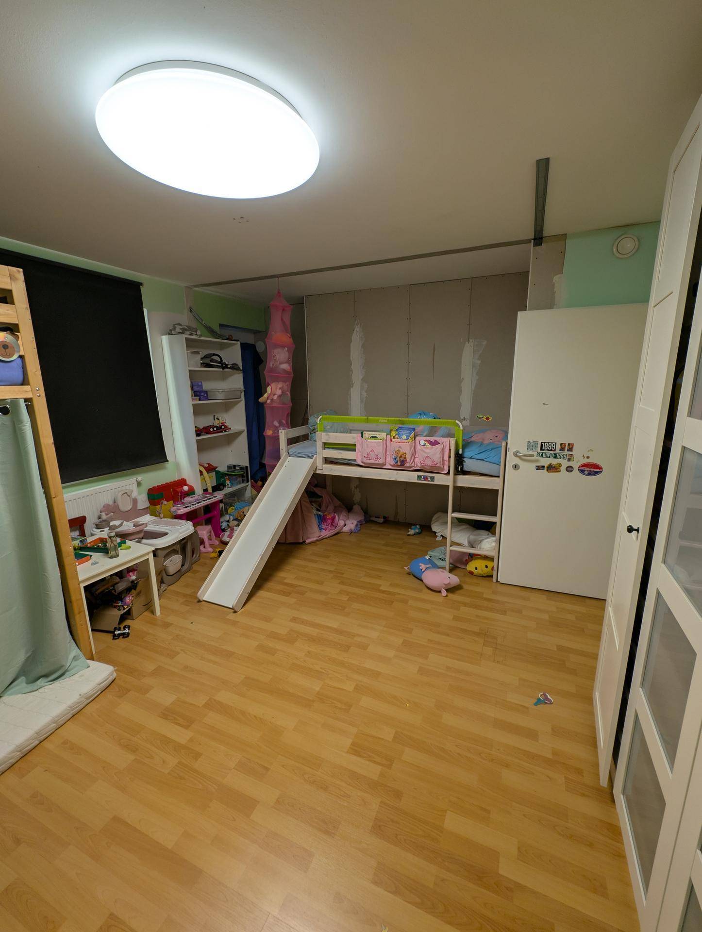 Helles Kinderzimmer mit Hochbett, Spielbereich und Kleiderschrank, bietet viel Platz für Kinder.