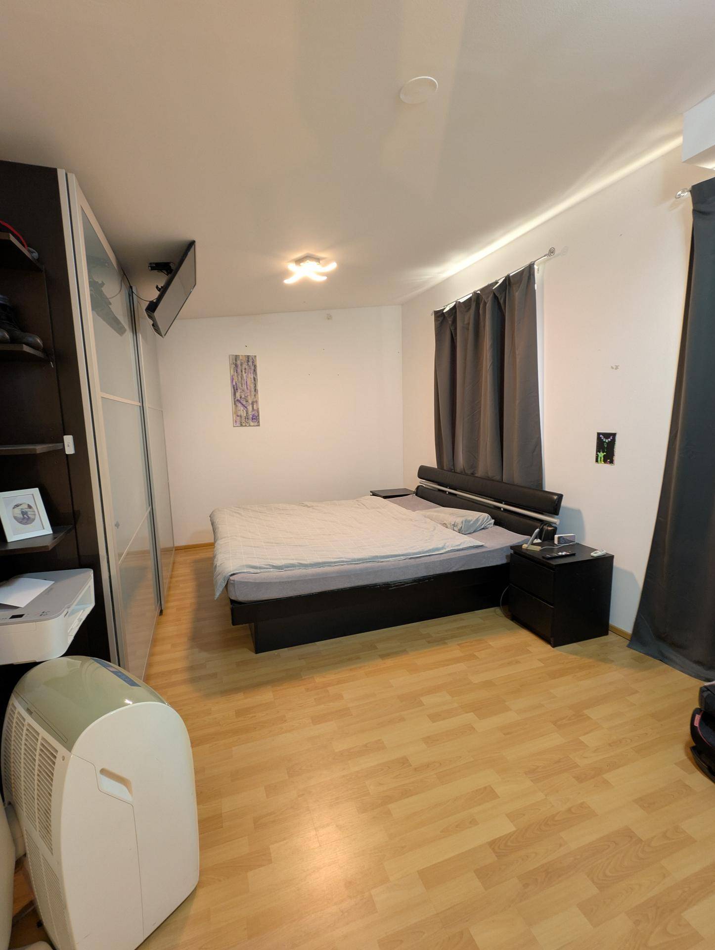 Schlafzimmer mit Doppelbett, Holzfußboden und Klimaanlage, bietet Komfort und Ruhe.