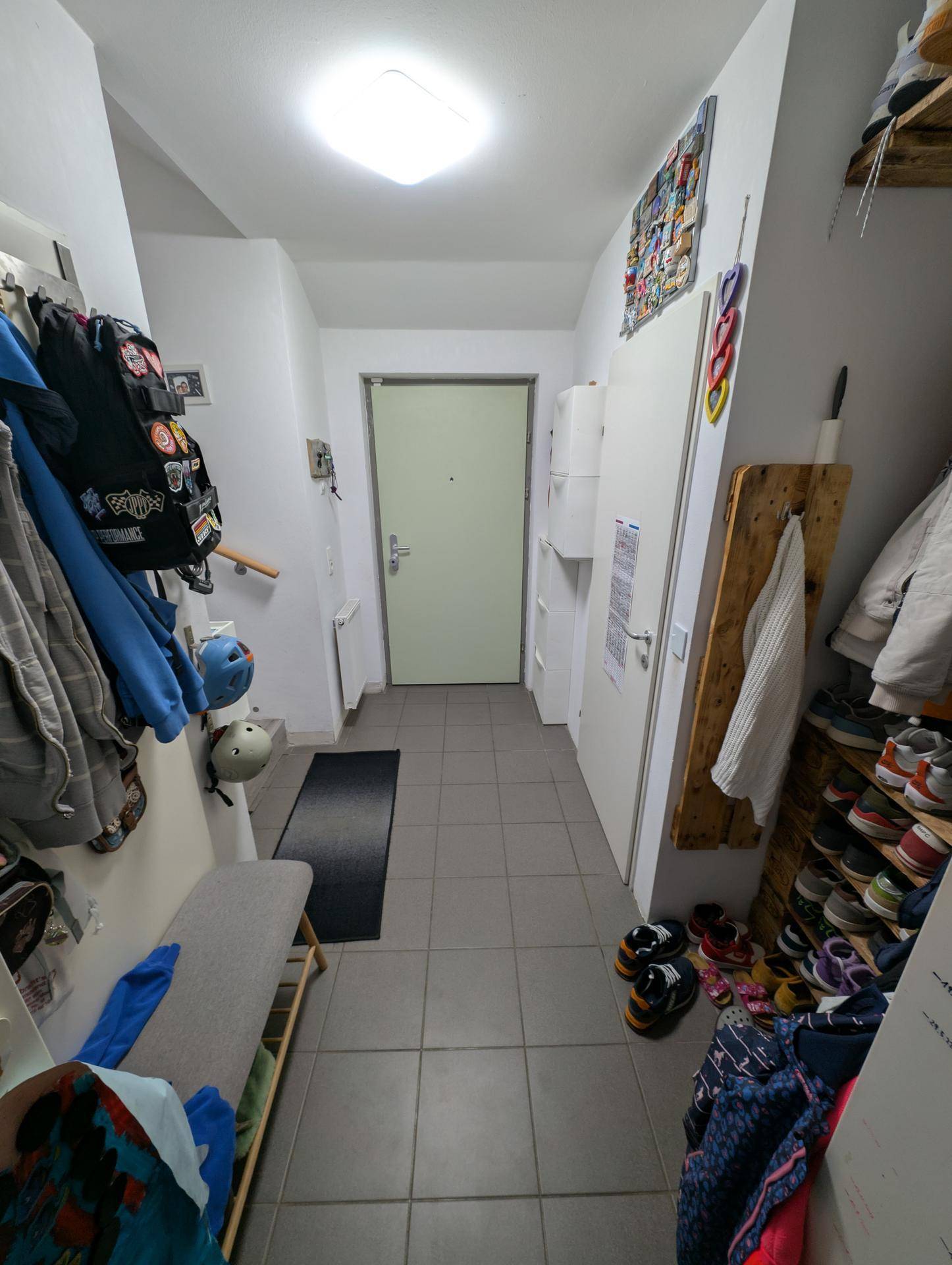Heller Flur mit Fliesenboden, Garderobe und praktischem Schuhregal, führt zum Eingangsbereich.