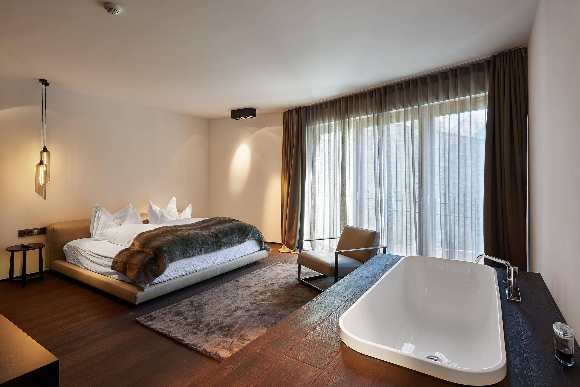 Geräumiges Schlafzimmer mit integrierter Badewanne, großen Fenstern und Holzboden.
