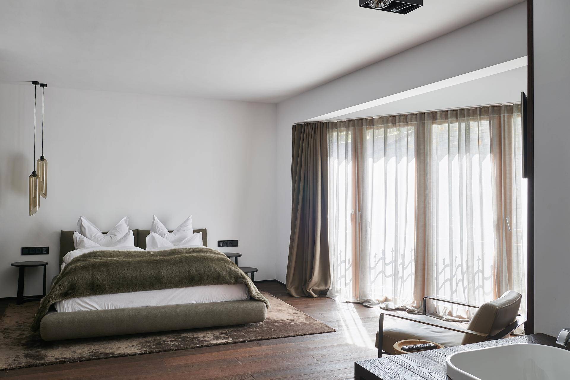 Helles Schlafzimmer mit großen Fenstern, die viel Tageslicht hereinlassen und Ausblick bieten.