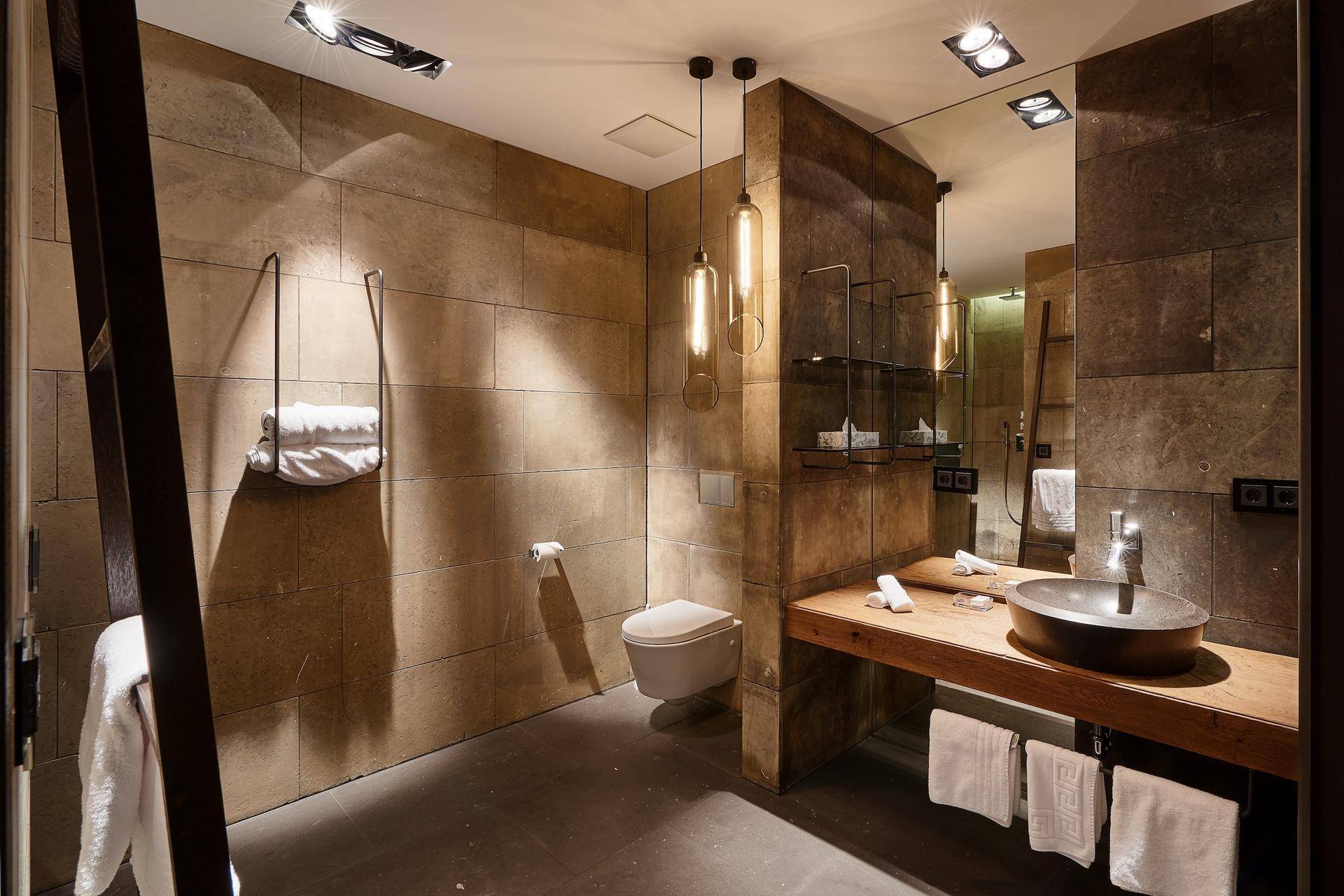 Elegantes Badezimmer mit Steinwänden, modernem Waschbecken und wandhängendem WC.
