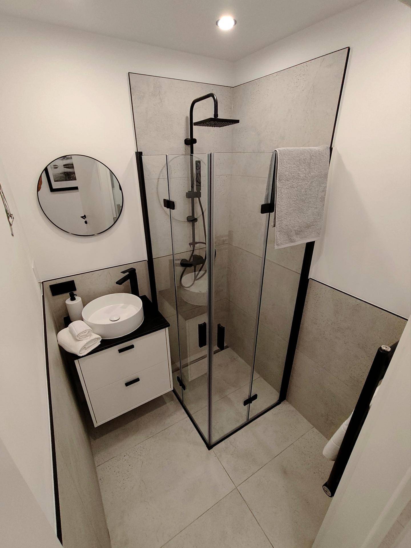 Modernes Badezimmer mit Eckdusche, Aufsatzwaschbecken und stilvollen schwarzen Armaturen.