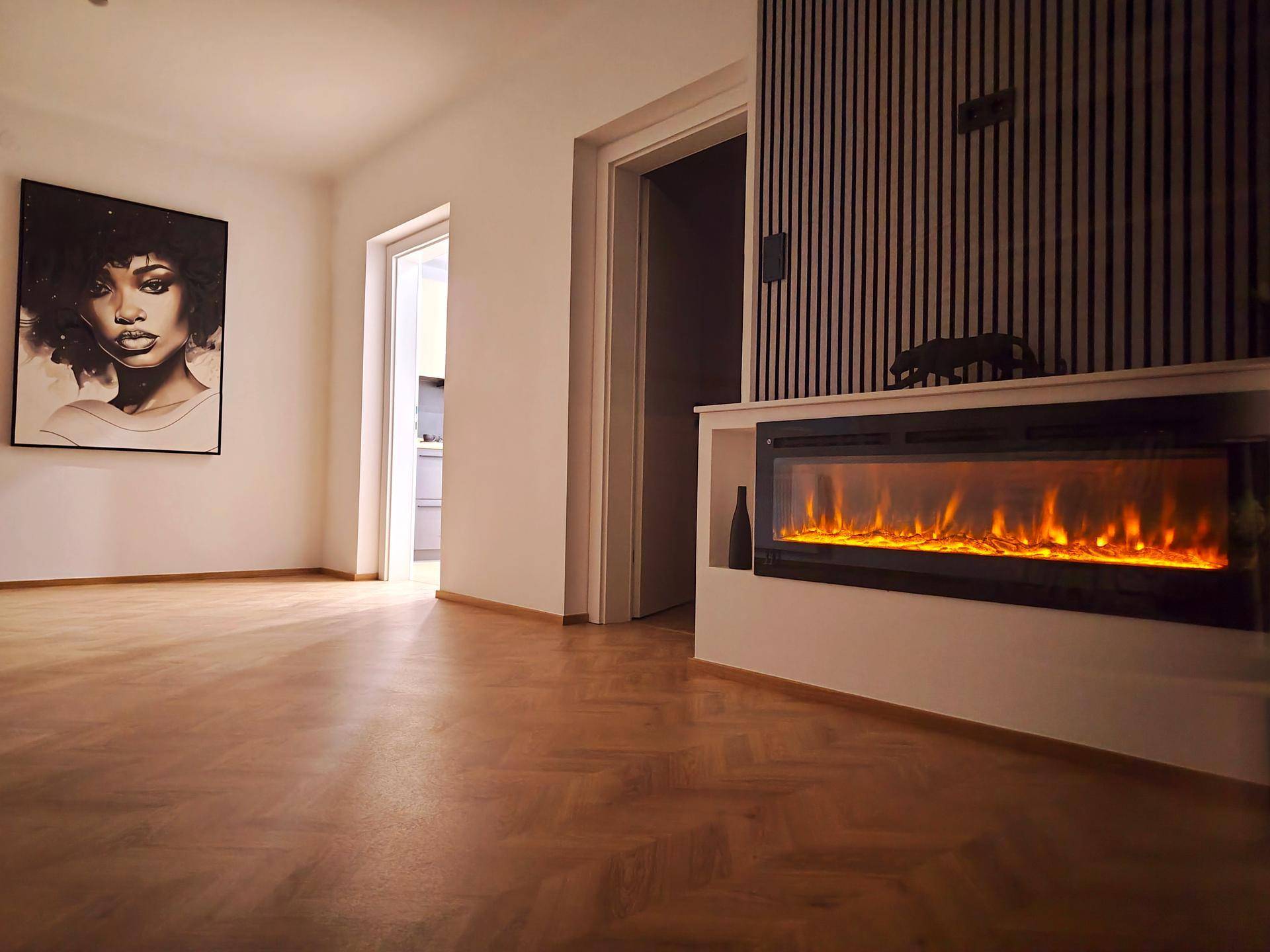 Gemütliches Wohnzimmer mit beleuchtetem Elektrokamin, Fischgrätparkett und moderner Kunst.