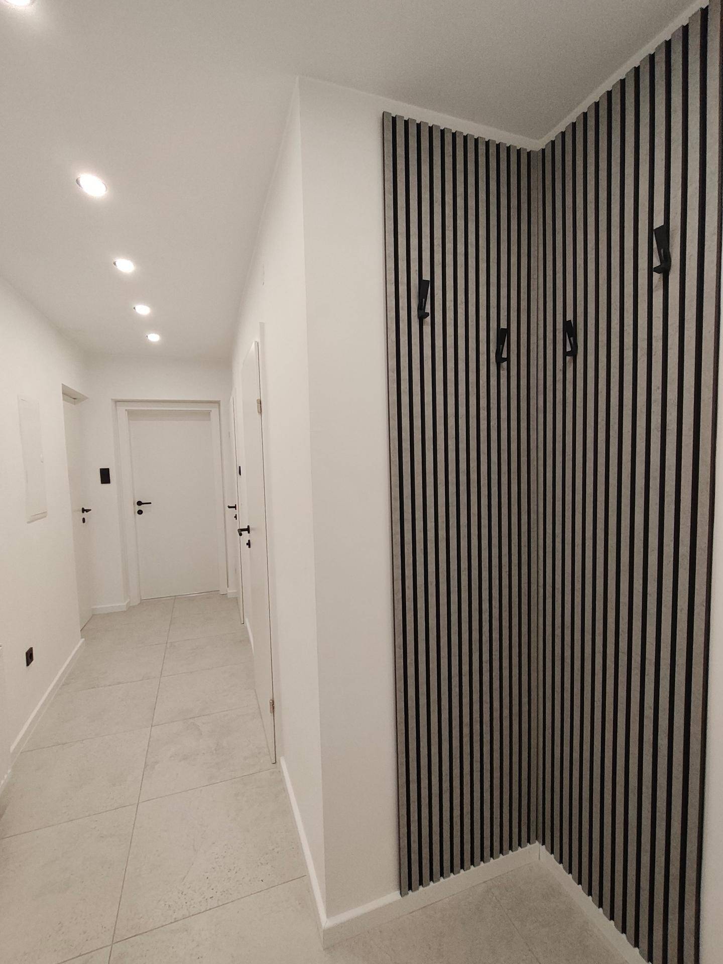 Moderner Flur mit Fliesenboden, Einbaustrahlern und einer stilvollen Garderobenwand.