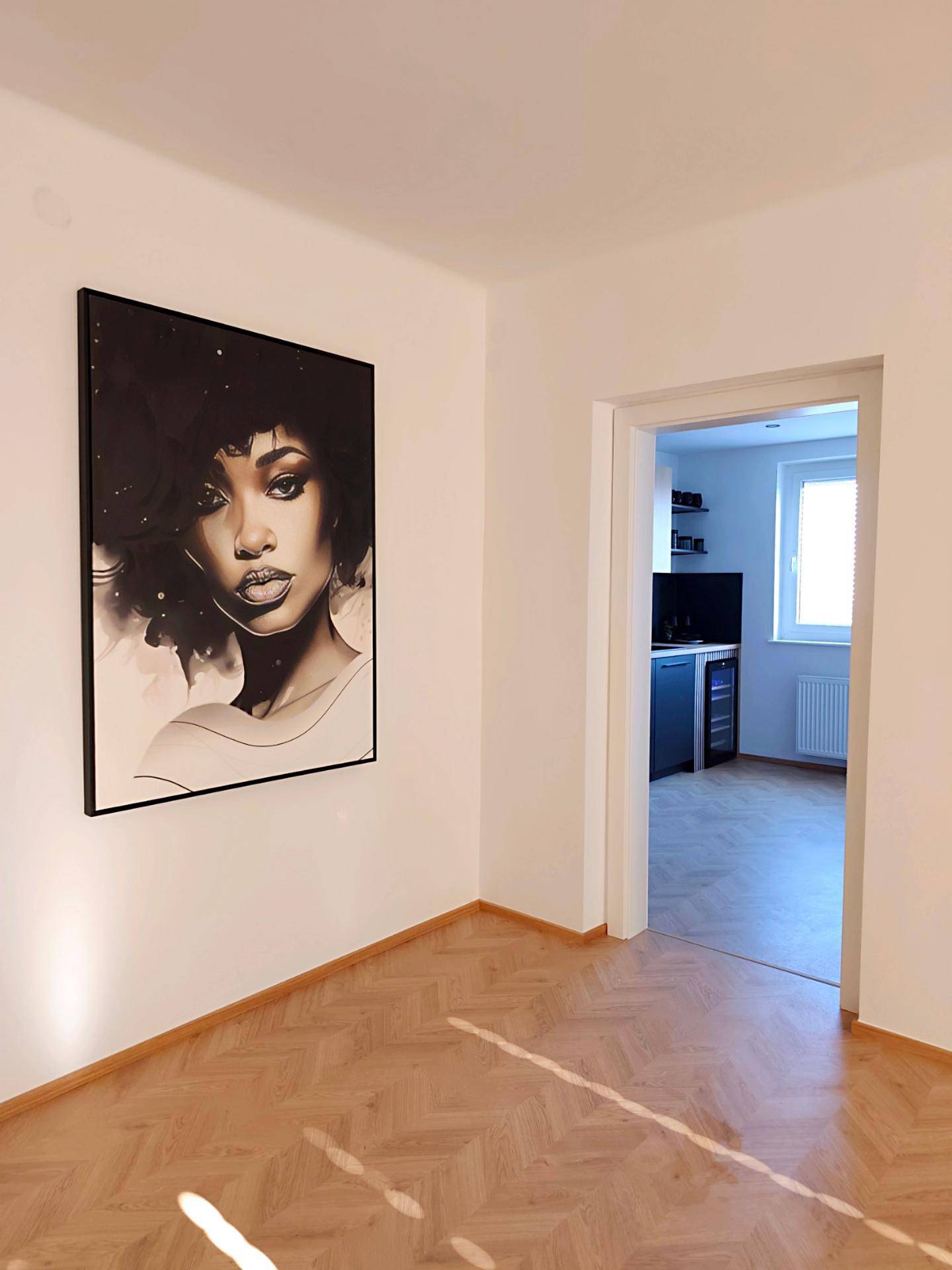 Ecke eines hellen Wohnzimmers mit großem Kunstwerk und Zugang zu einem weiteren Raum.