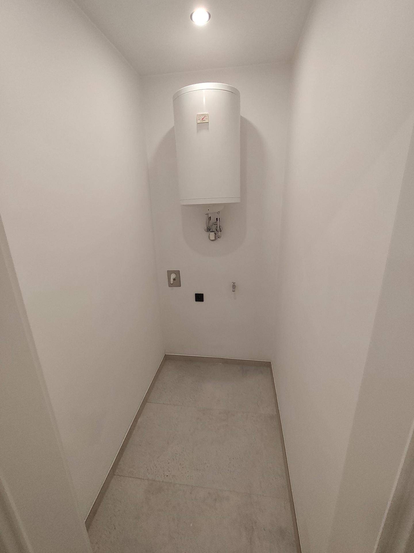Praktischer Hauswirtschaftsraum mit Warmwasserboiler und pflegeleichtem Fliesenboden.