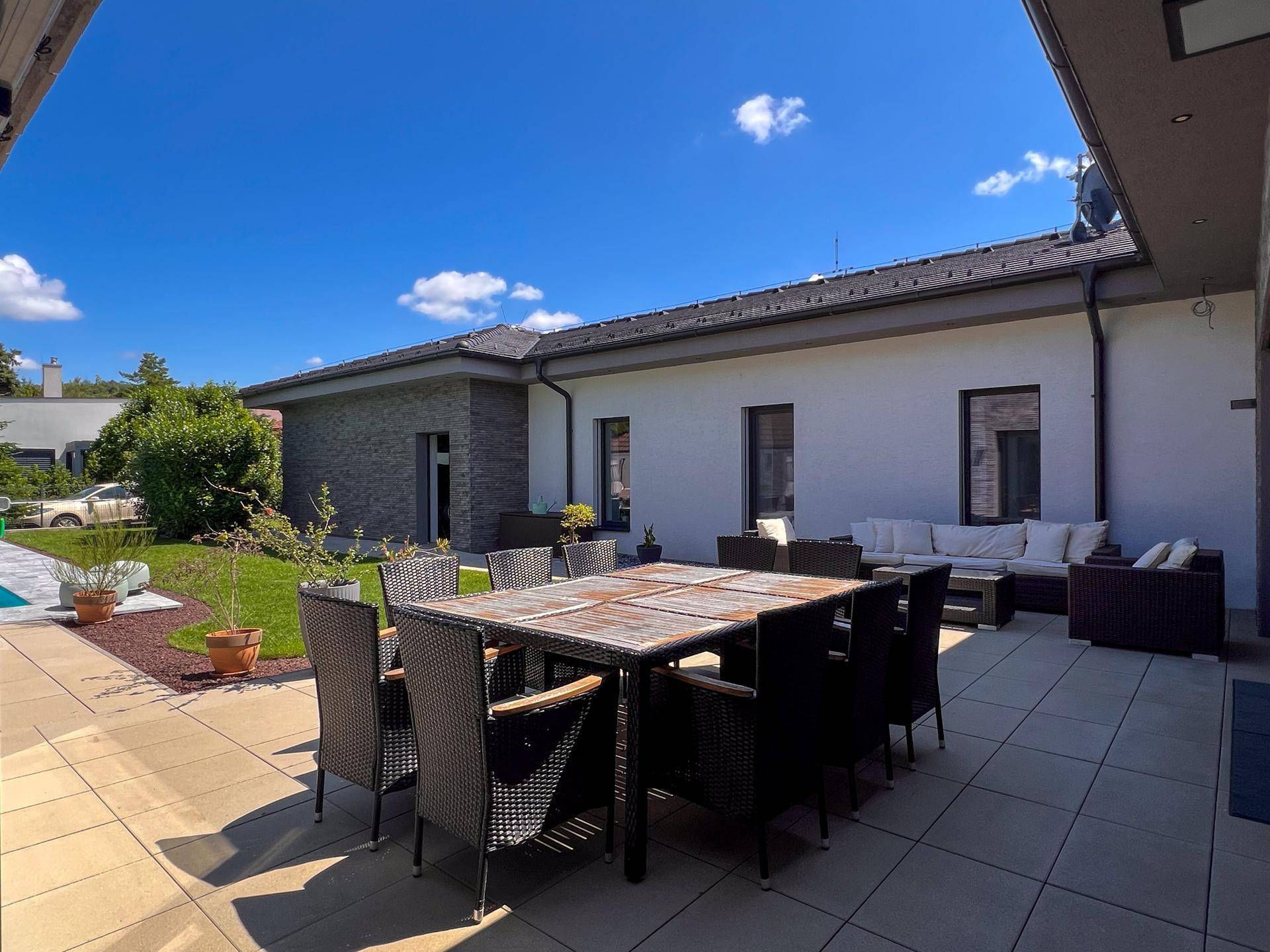 Große, sonnige Terrasse mit Essbereich und Blick auf den Garten und Poolbereich.