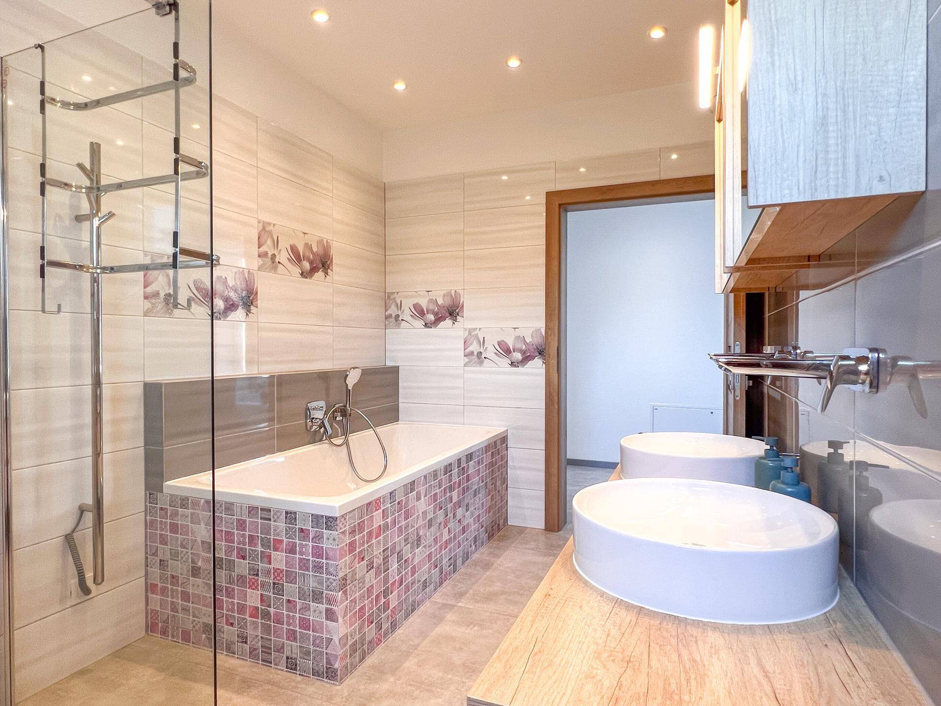 Geräumiges Badezimmer mit Badewanne, Dusche und Doppelwaschbecken.