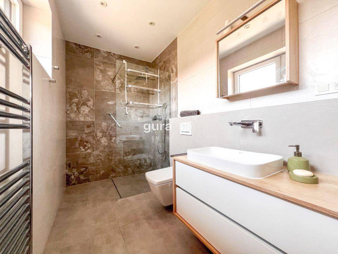 Modernes Badezimmer mit begehbarer Dusche, Wand-WC und Holzwaschtisch mit Spiegel.