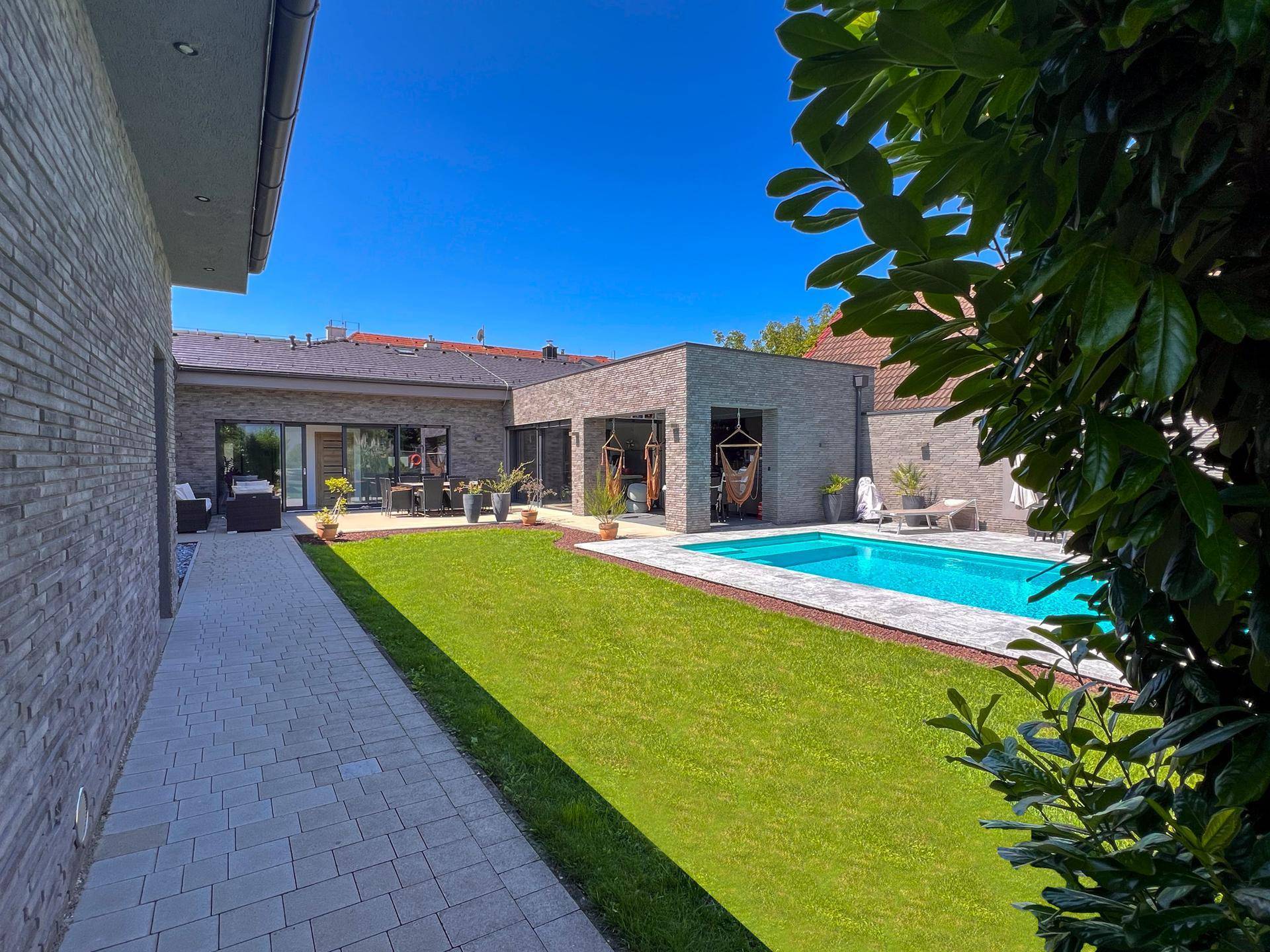 Gepflegter Gartenbereich mit Pool, Rasenfläche und moderner Architektur des Hauses.