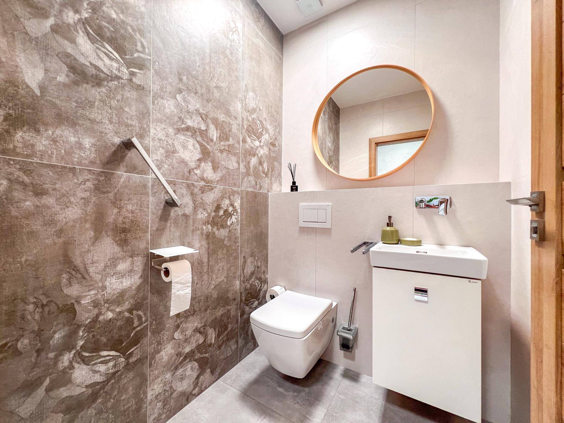 Modernes Gäste-WC mit Wand-WC, kleinem Waschbecken und stilvollen Fliesen.