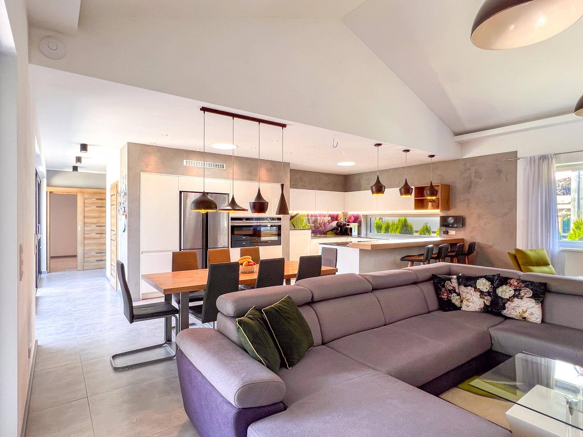 Moderner Wohn-Essbereich mit offener Küche, Esstisch und großem Sofa.