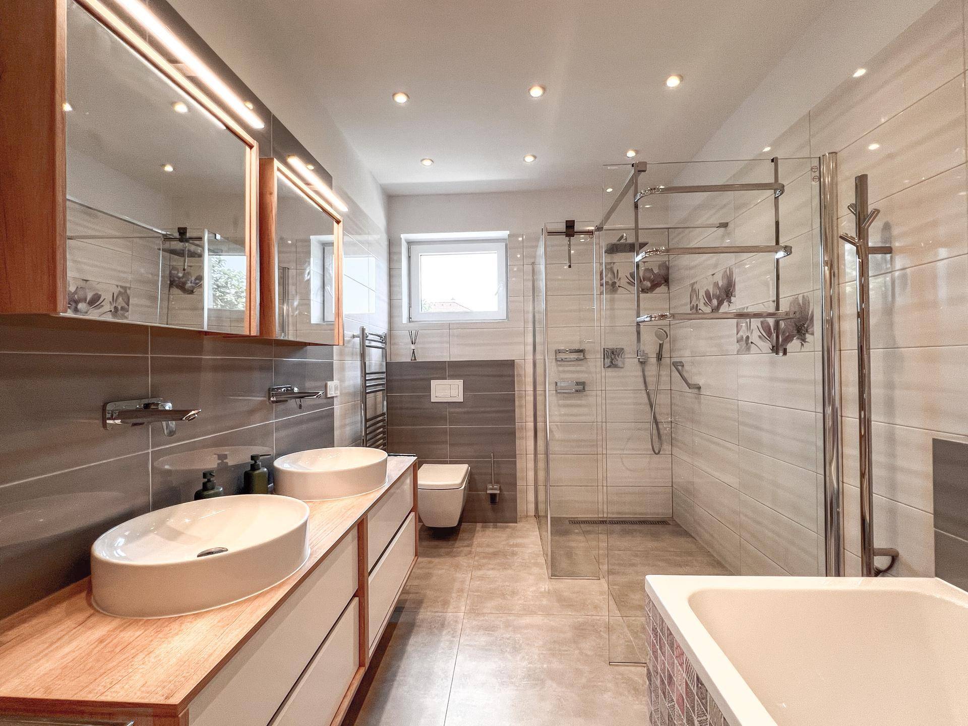 Helles Badezimmer mit Doppelwaschbecken, großer Dusche und Fenster.