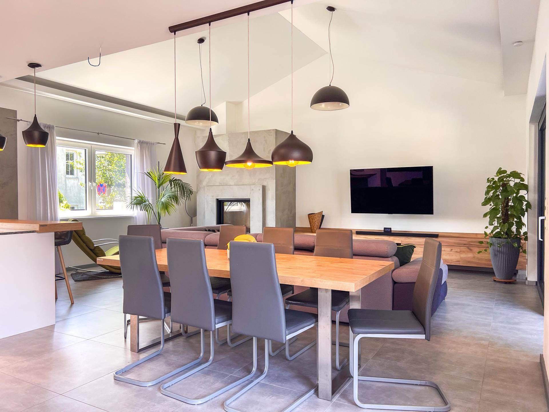 Geräumiger Wohn-Essbereich mit großem Esstisch, bequemer Couch und Kamin.
