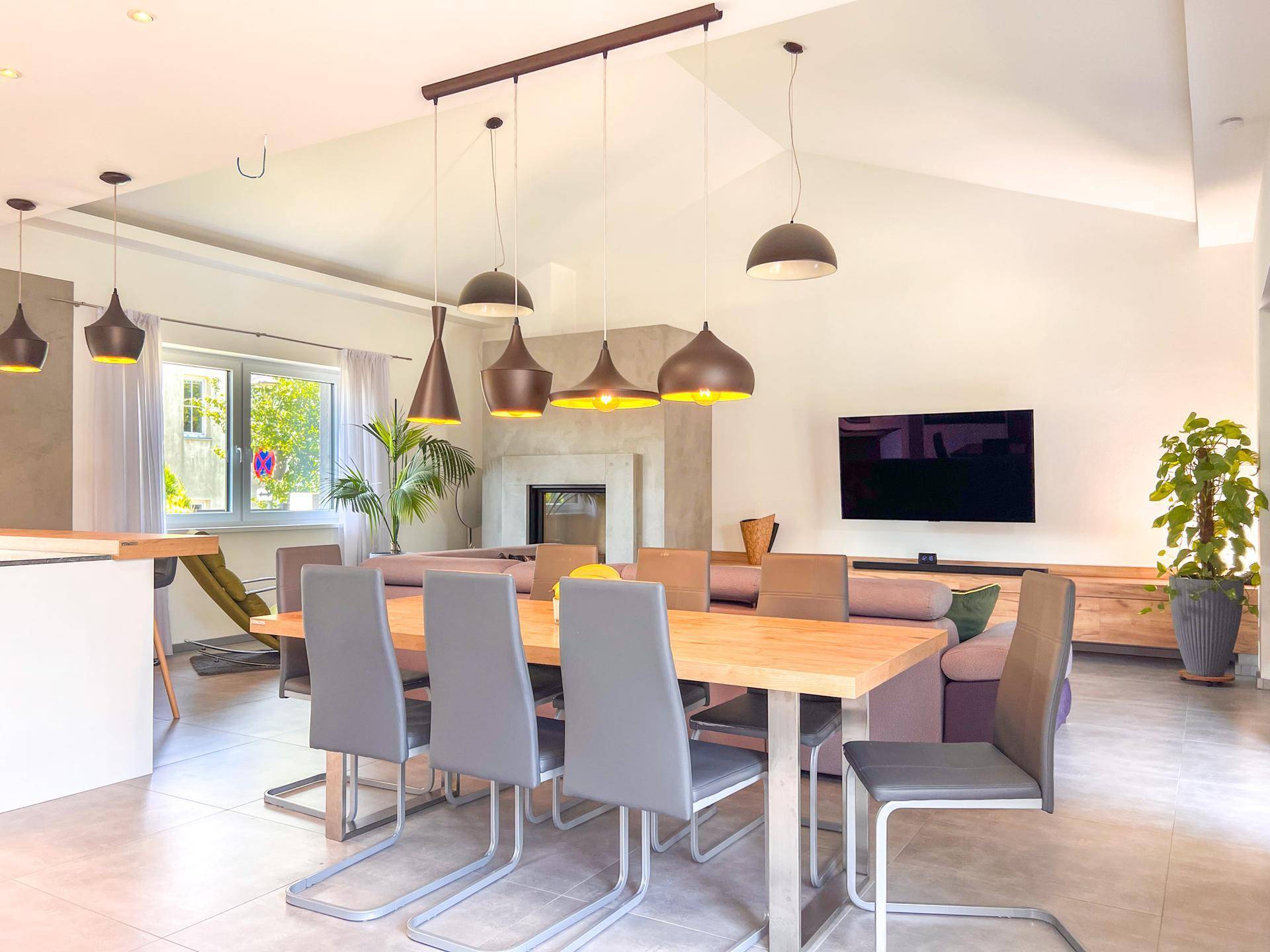 Geräumiger Wohn-Essbereich mit großem Esstisch, bequemer Couch und Kamin.