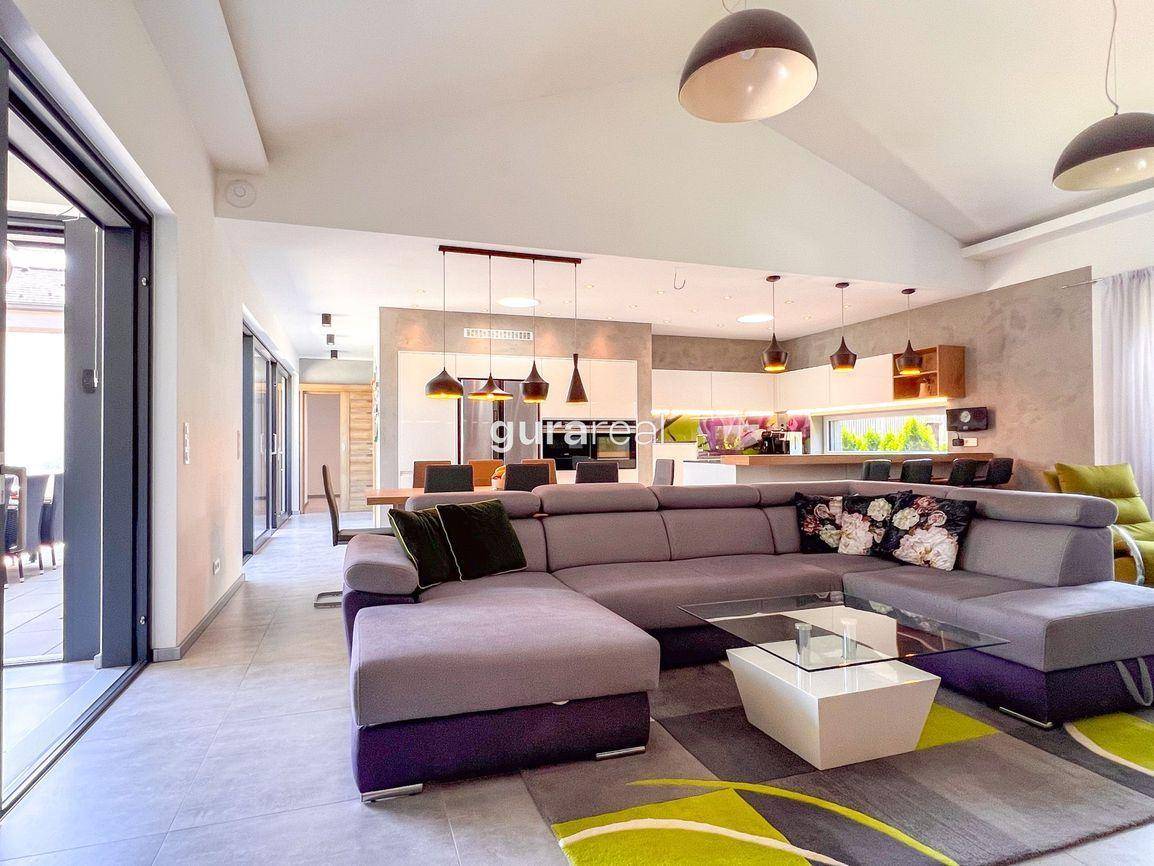 Heller offener Wohnbereich mit großem Sofa, Essbereich und moderner Küche im Hintergrund.
