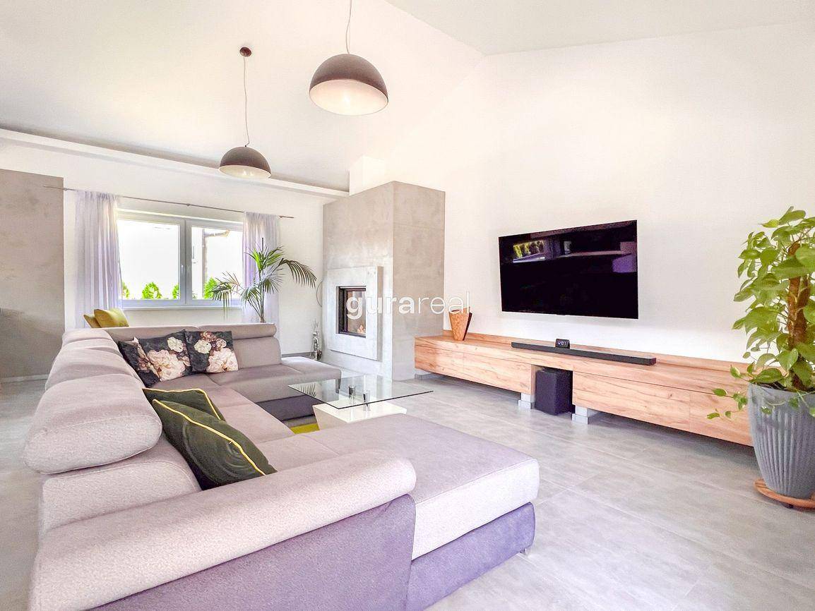 Gemütliches Wohnzimmer mit großem Ecksofa, modernem Kamin und Fernseher an der Wand.