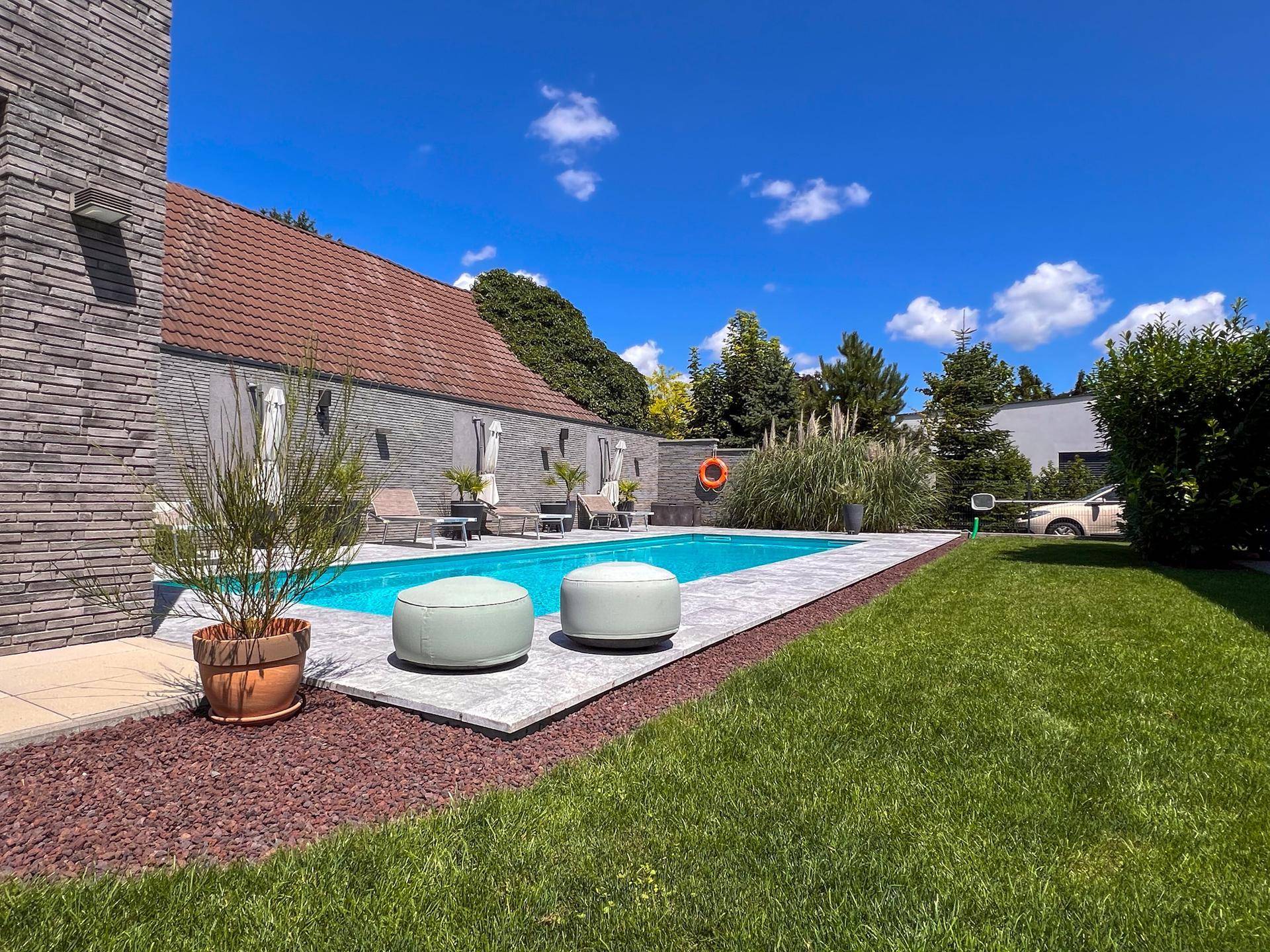 Gepflegter Garten mit Pool, Liegeflächen und mediterraner Bepflanzung.