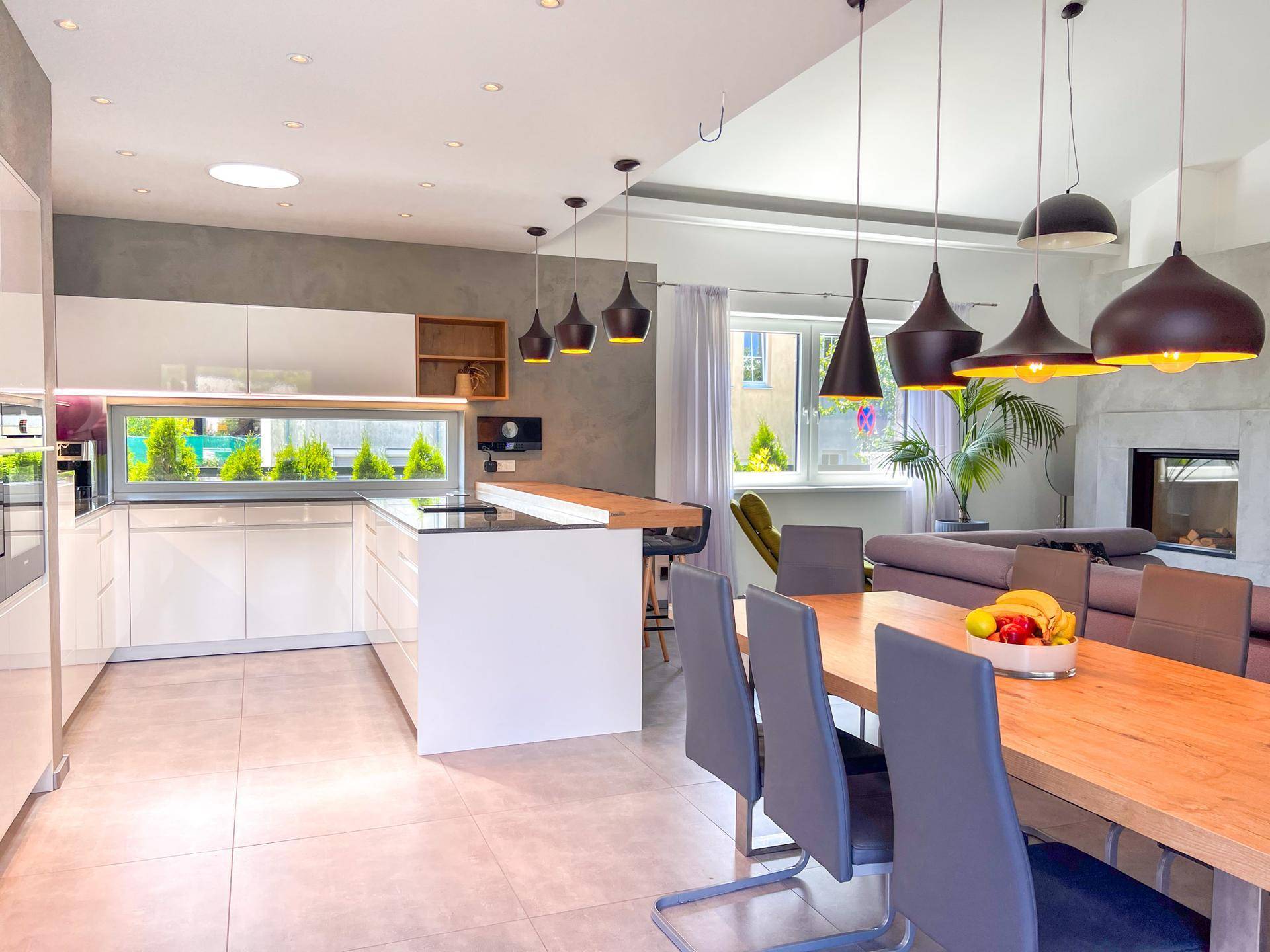 Offener Wohn-Essbereich mit moderner Küche, Esstisch und stilvollen Pendelleuchten.