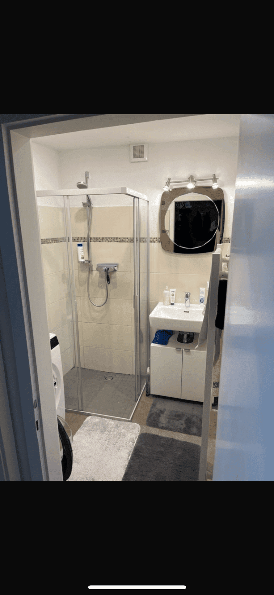 Modernes Badezimmer mit Duschkabine, Waschbecken und Spiegel, funktional und hell.