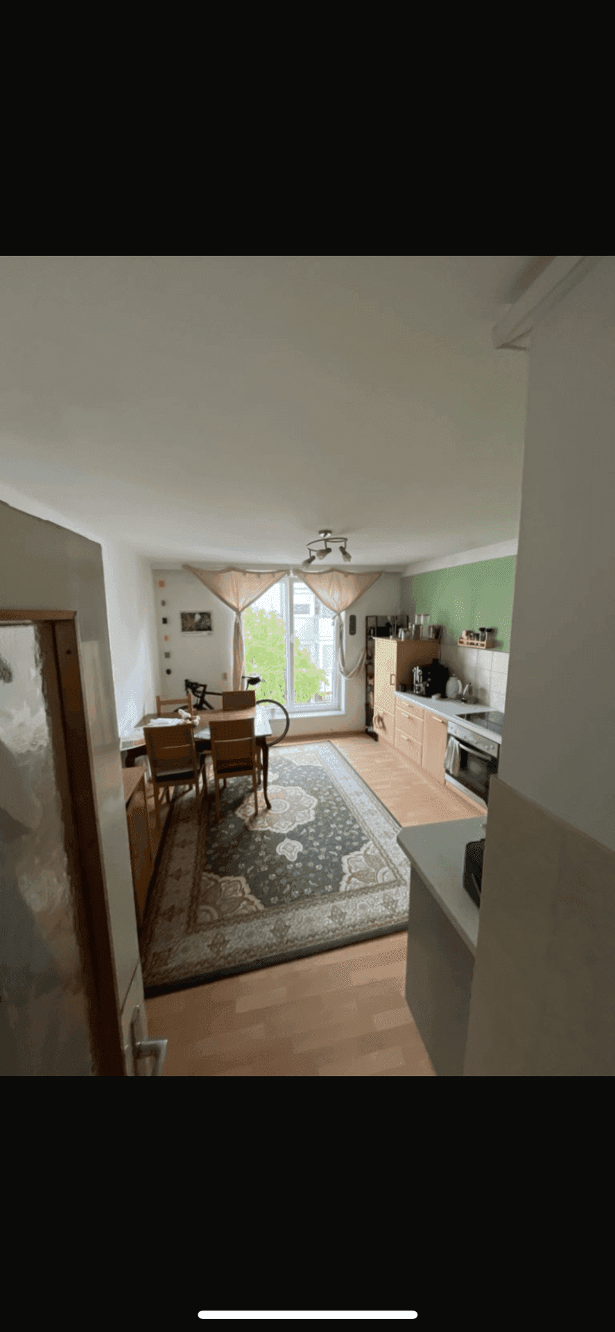 Helle Küche mit Essbereich, Holzboden und Fenster mit Blick ins Grüne.