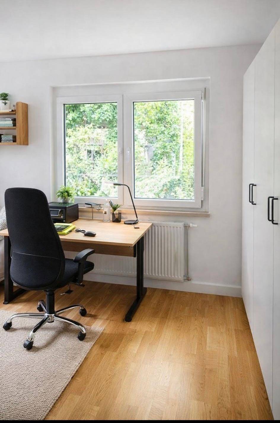 Helles Arbeitszimmer mit Holzschreibtisch, Bürostuhl und Blick ins Grüne.