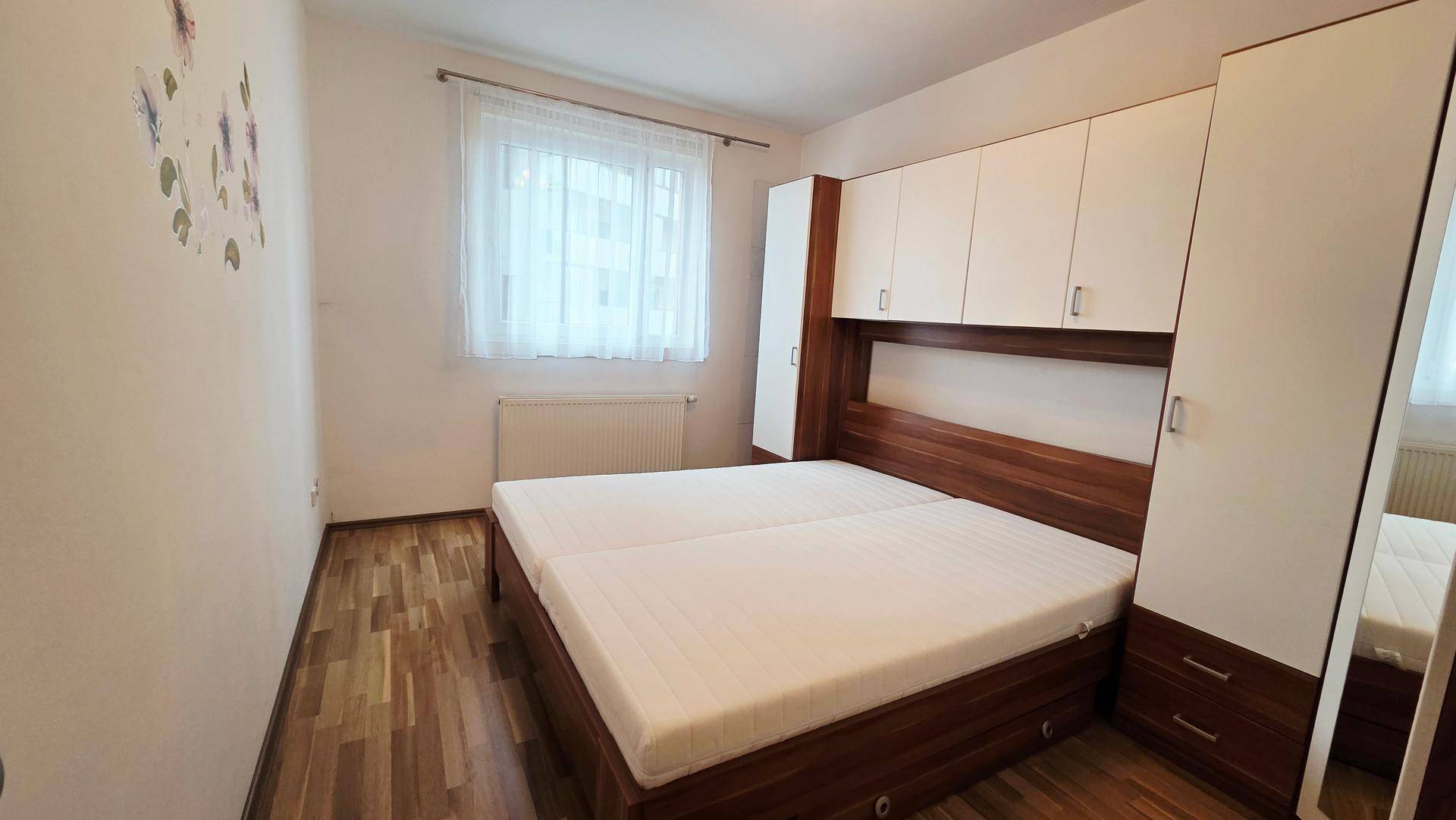Schlafzimmer mit Doppelbett, integrierten Schränken und einem Fenster für natürliches Licht.