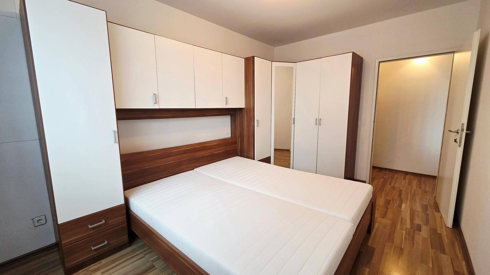 Geräumiges Schlafzimmer mit umfangreichen Einbauschränken und Holzboden.
