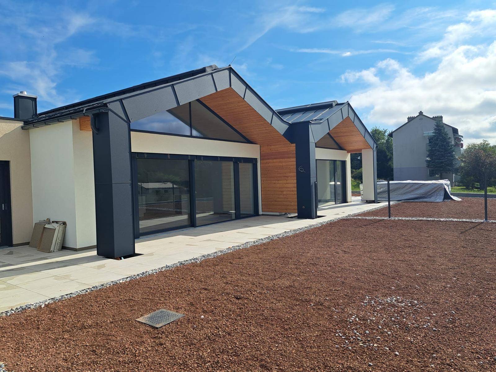 Moderne Architektur mit Holzverkleidung und großen Glasfronten unter blauem Himmel.