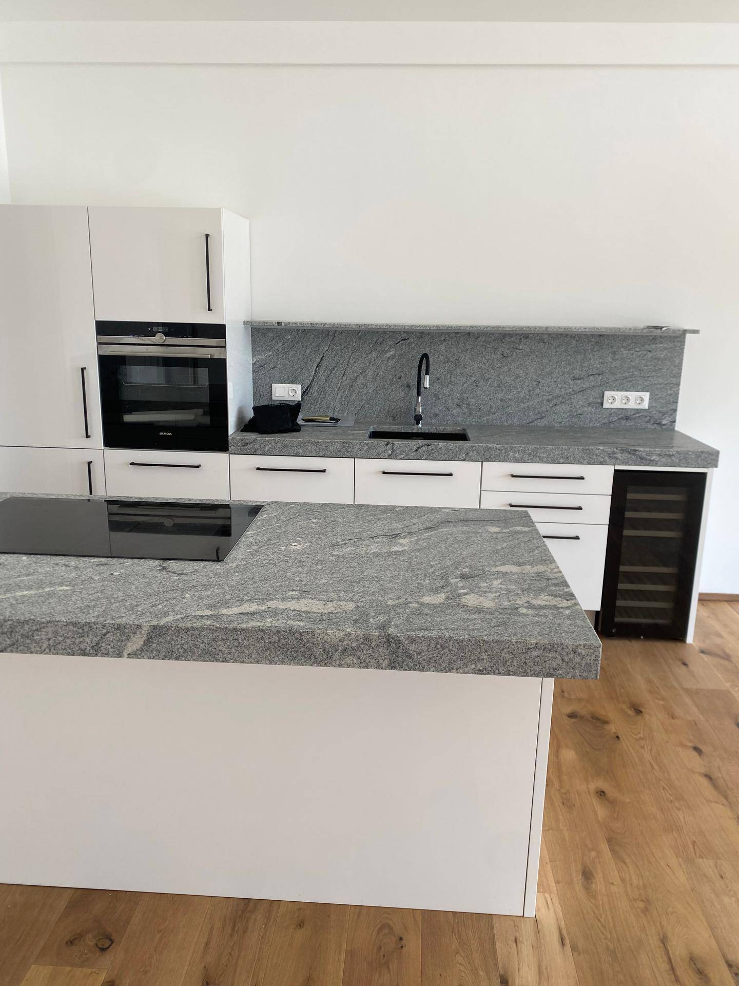 Moderne Küche mit Kochinsel, Granitarbeitsplatten und integrierten Geräten.