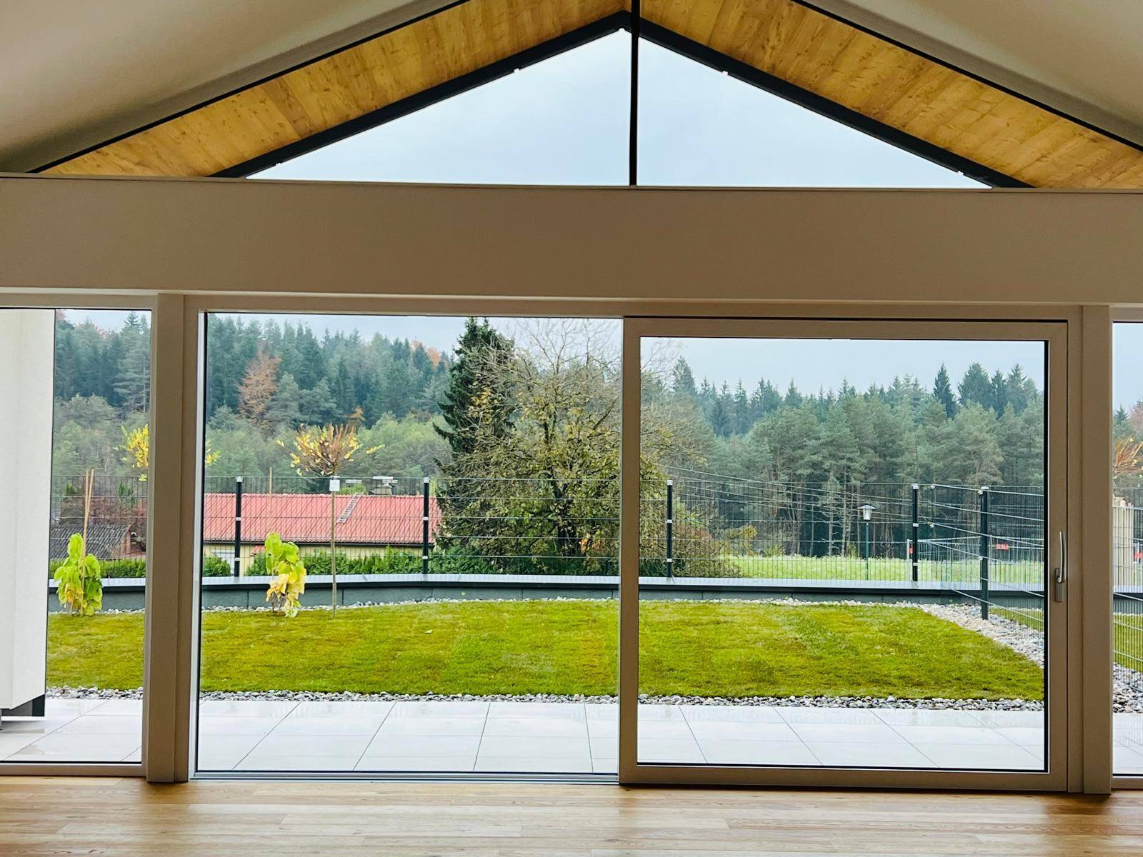 Heller Wohnbereich mit Holzboden und großen Schiebetüren, die den Zugang zur Terrasse und zum Garten ermöglichen.