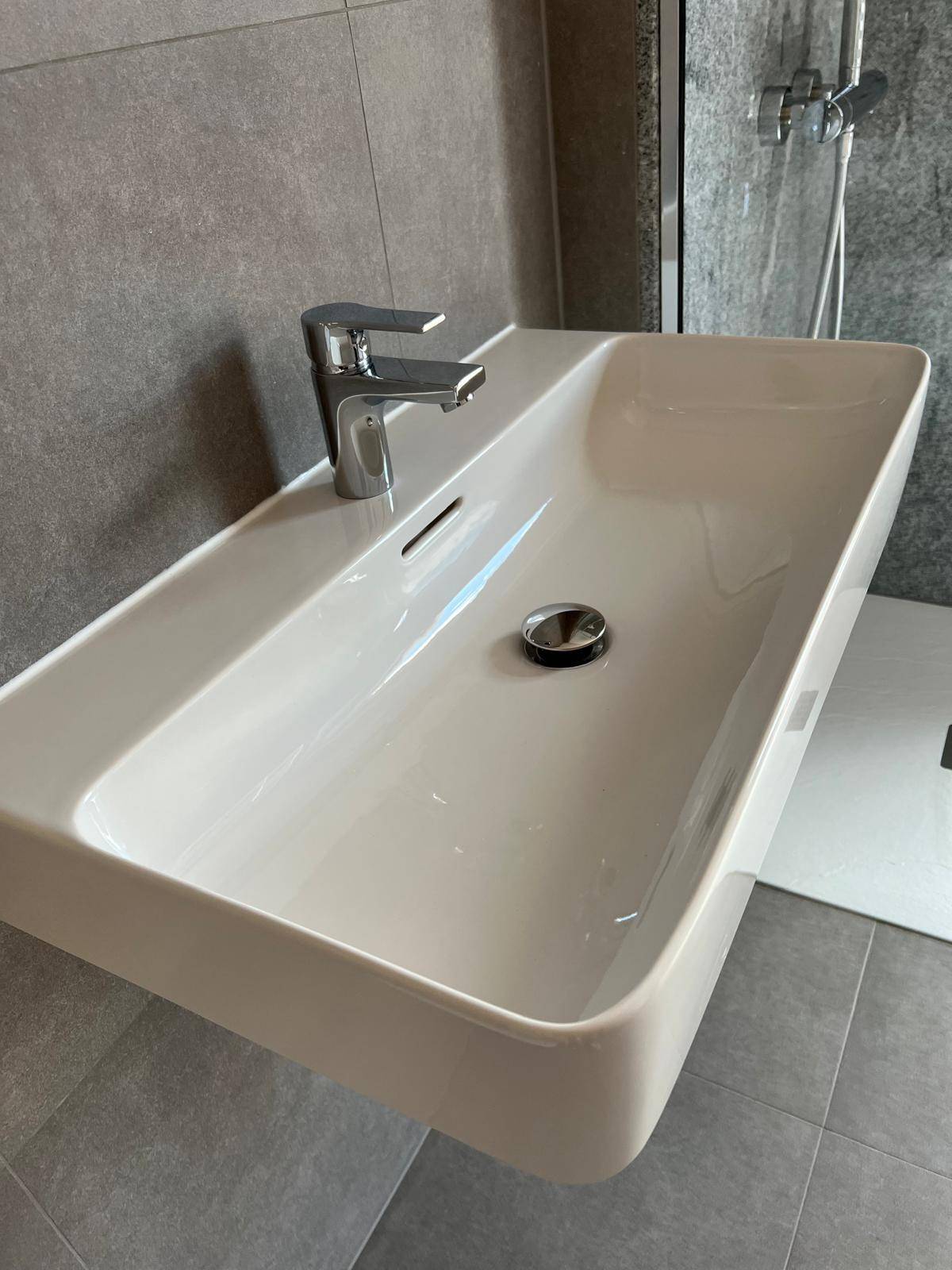 Nahaufnahme eines modernen Waschbeckens mit elegantem Wasserhahn in einem gefliesten Badezimmer.
