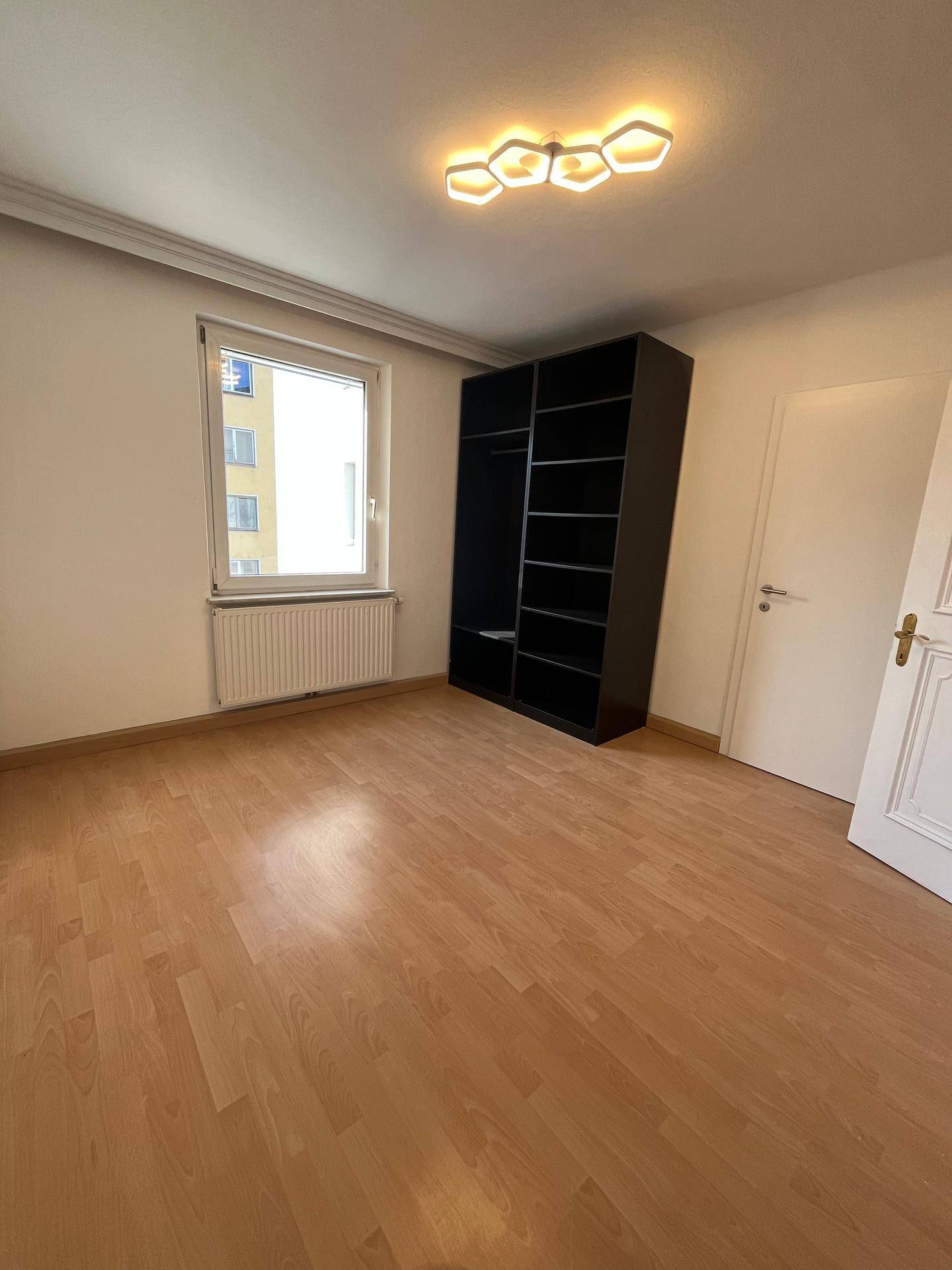 Geräumiges Schlafzimmer mit hellem Holzfußboden und einem praktischen offenen Kleiderschrank.