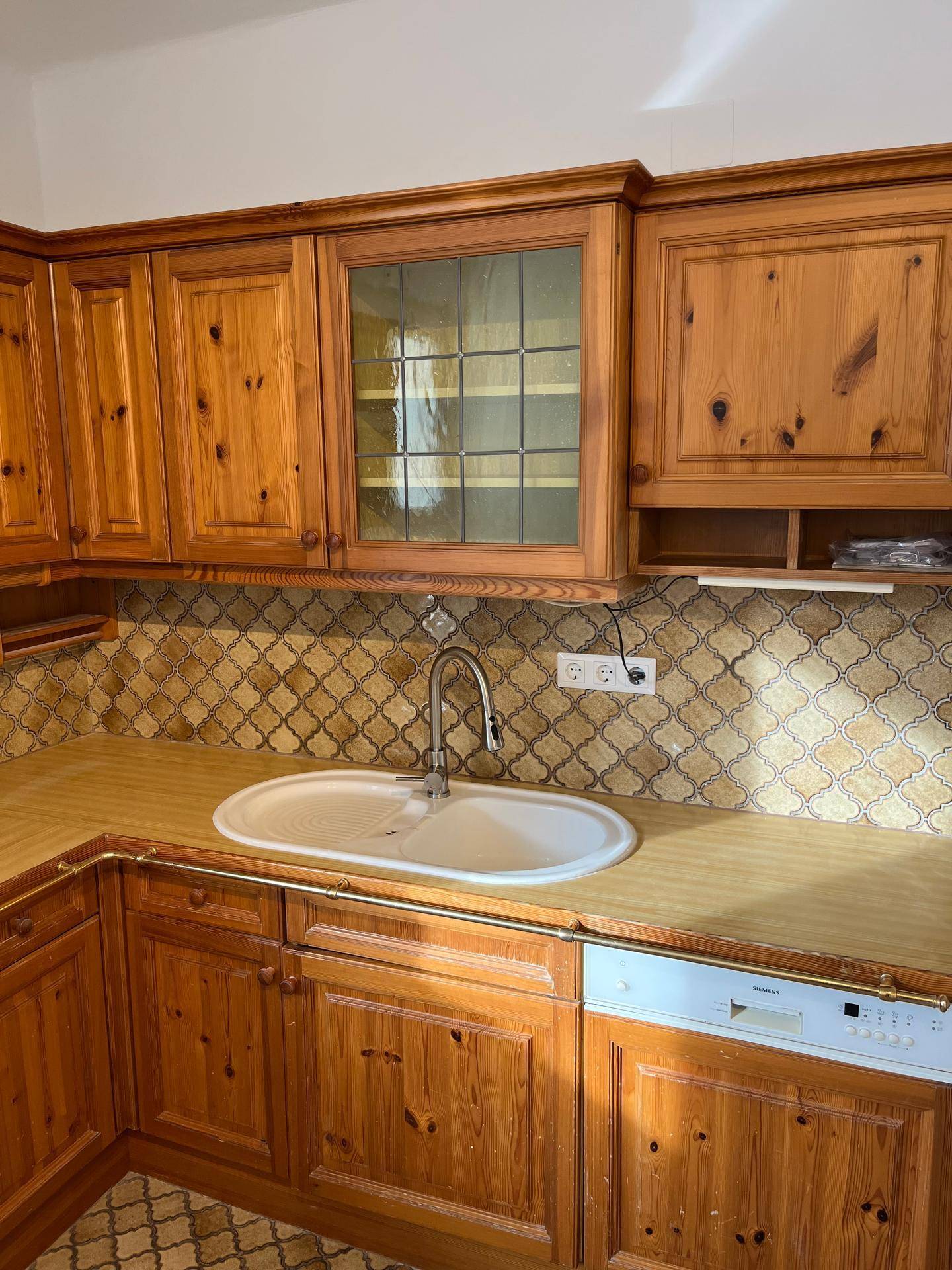 Detailansicht der Küche mit Spülbecken, Armatur, Geschirrspüler und gemustertem Fliesenspiegel.