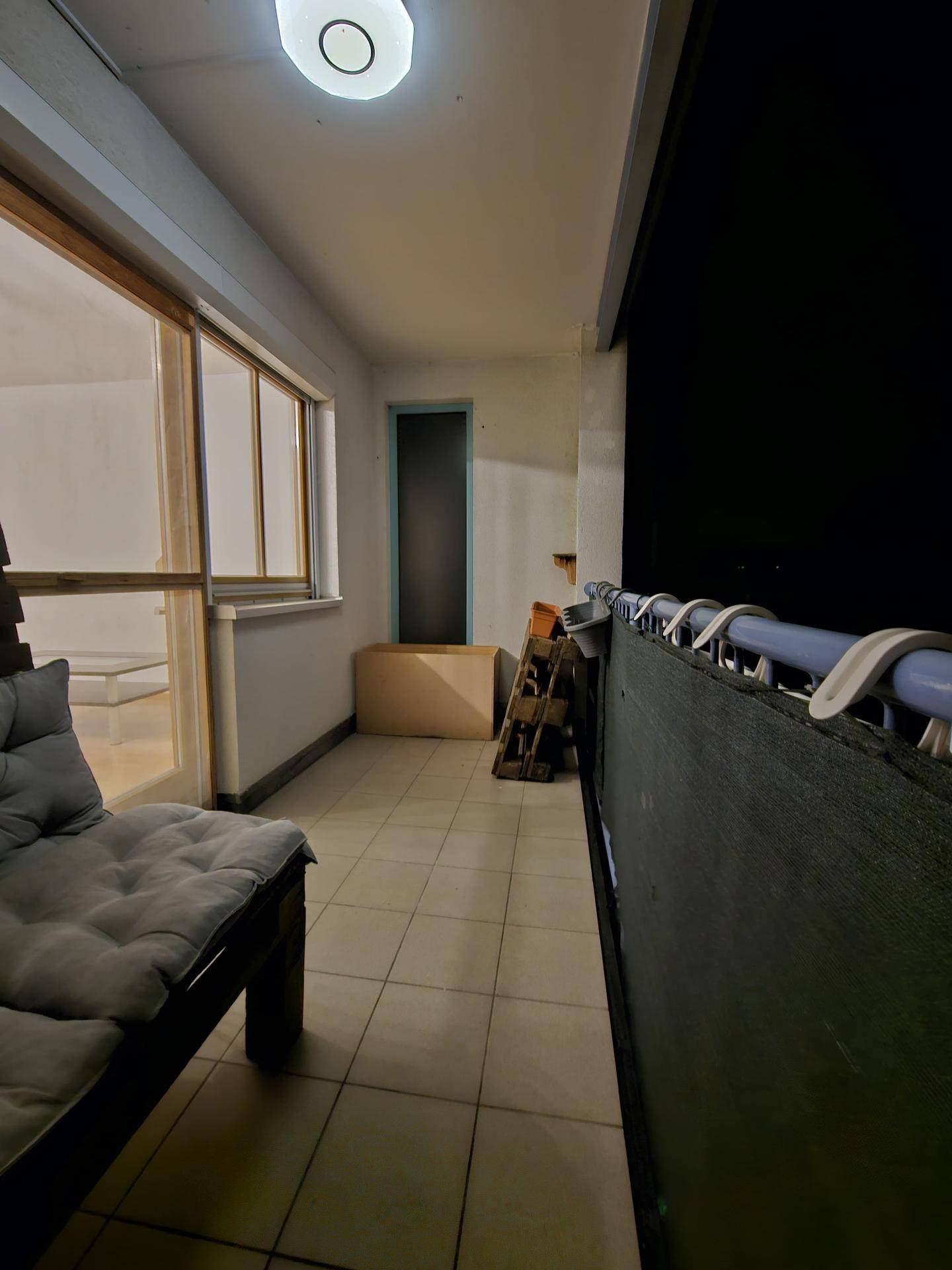 Balkon bei Nacht mit Fliesenboden und Blick auf den dunklen Außenbereich.